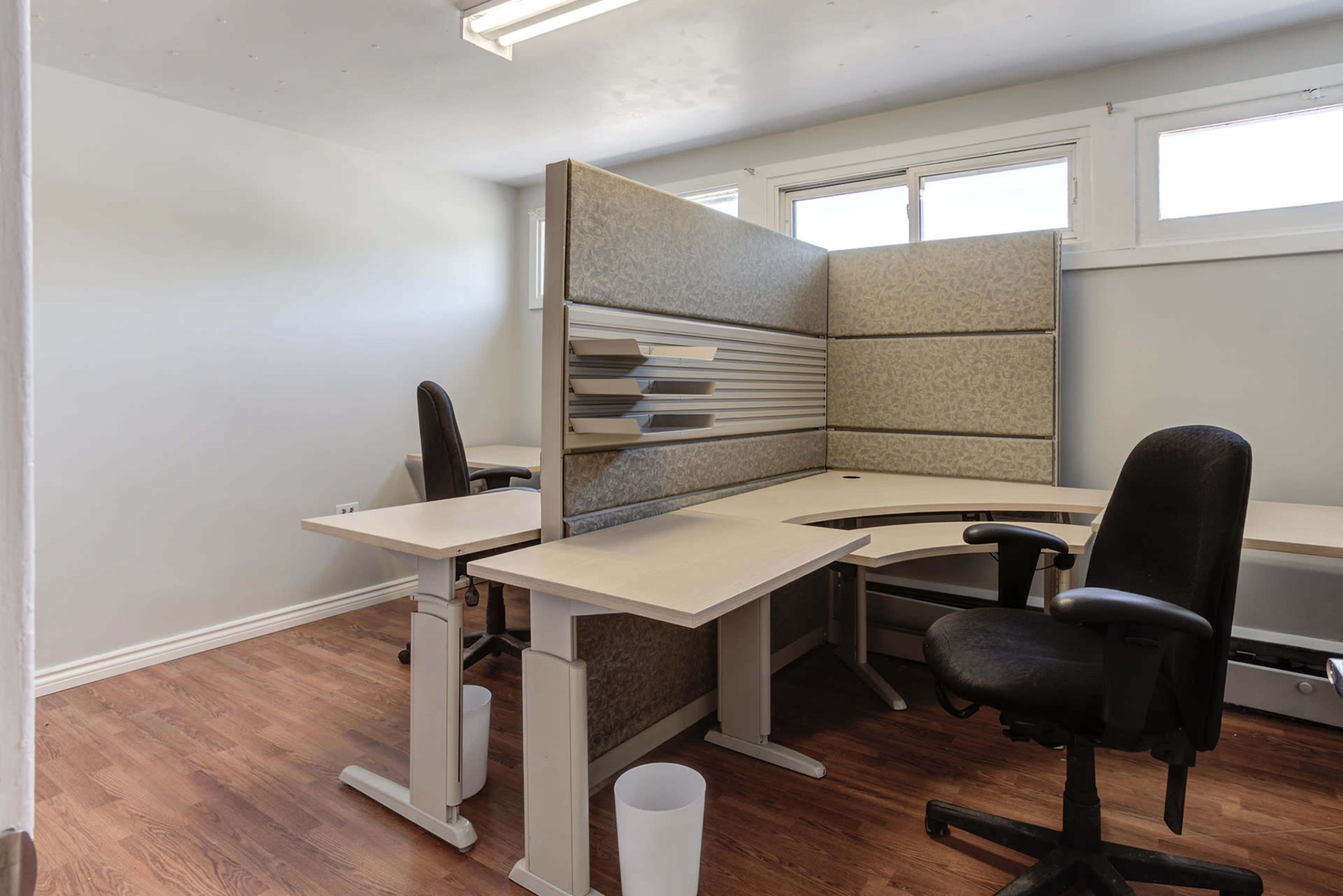 A small office space with two chairs and a corner desk separated by a panel.