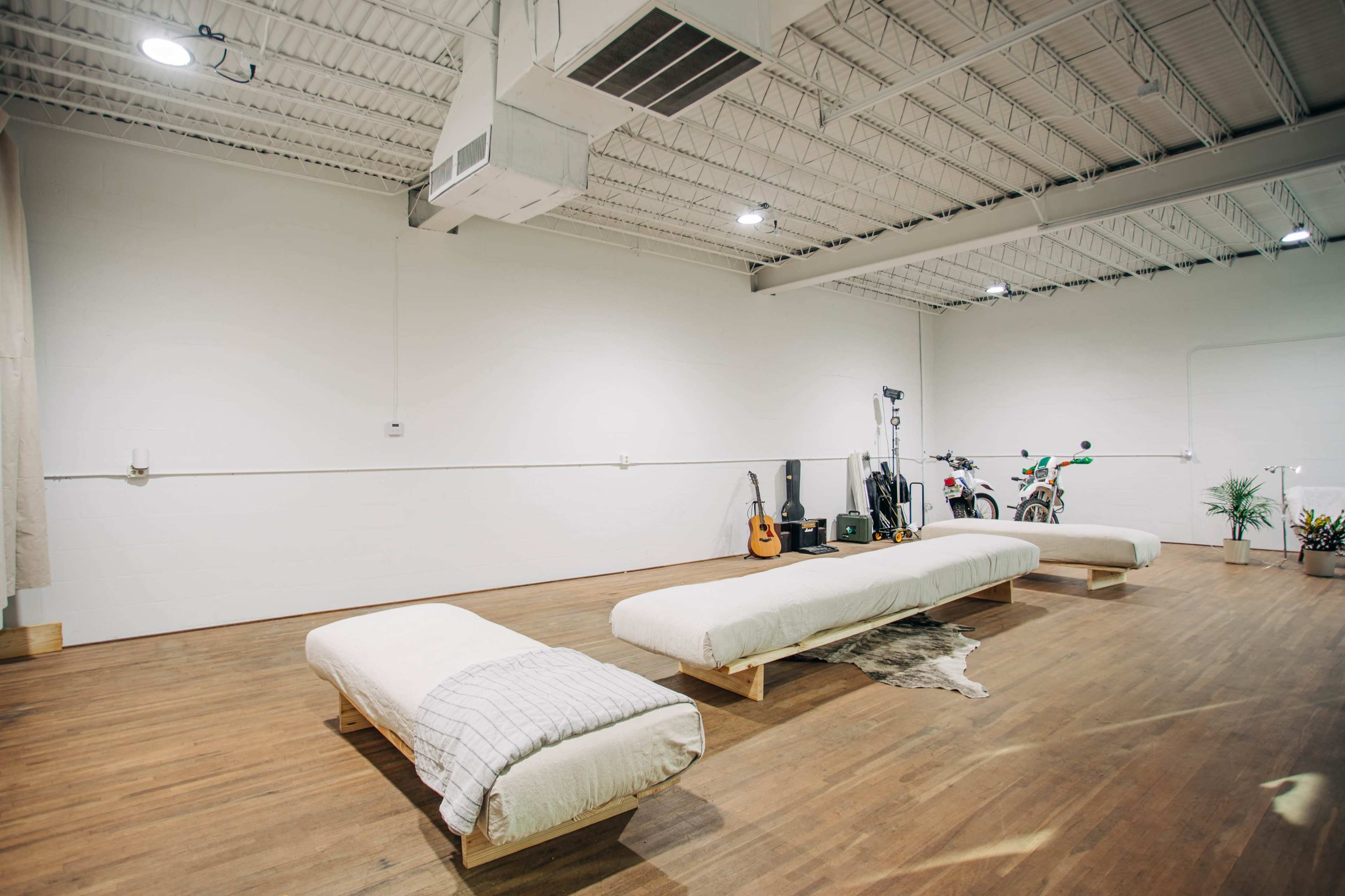 A spacious, minimalist room with three low wooden platforms and various musical instruments and a bicycle against the wall.