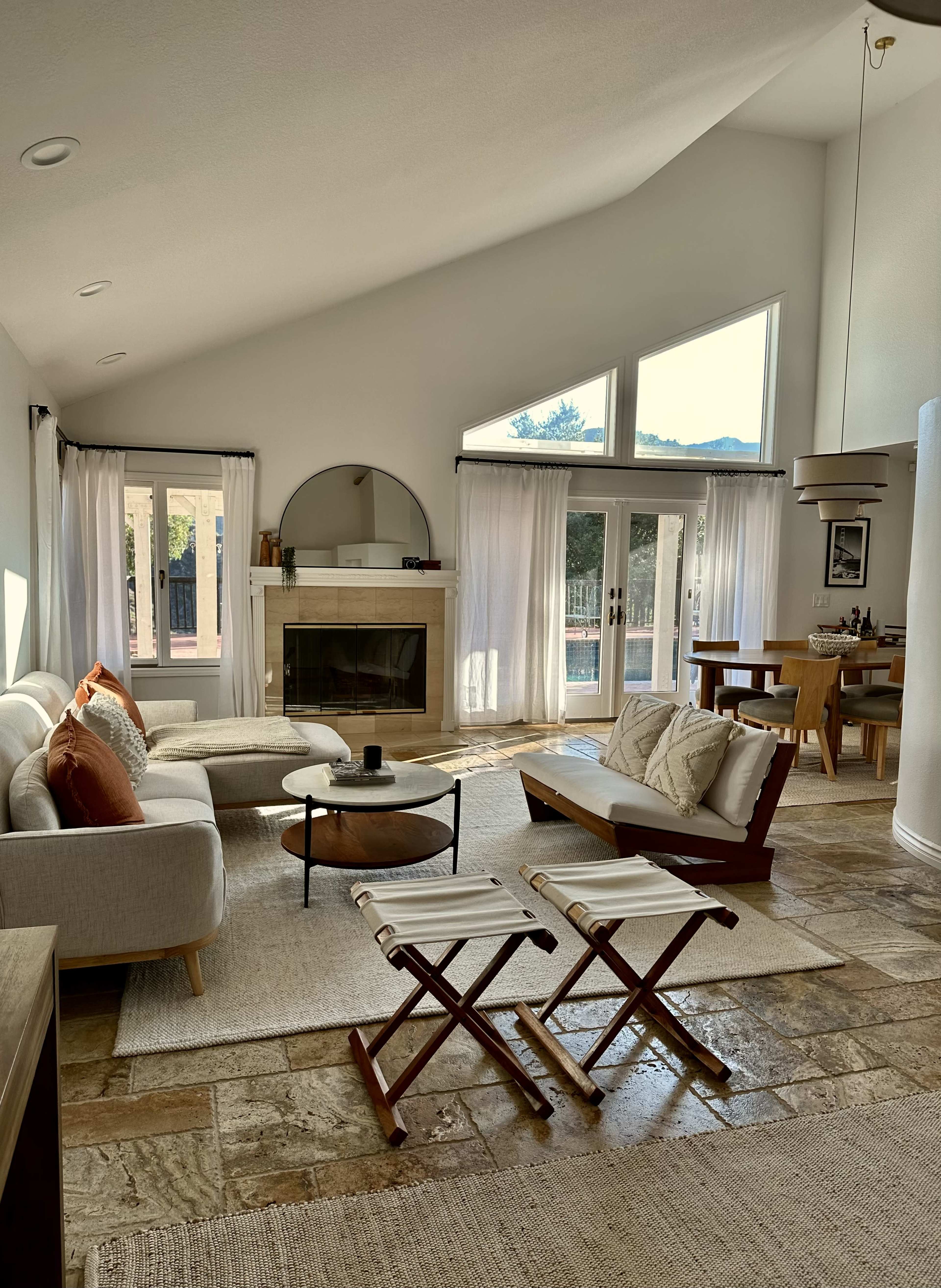 The room features a spacious living area with a fireplace, large windows, and modern furniture arranged around a central coffee table.