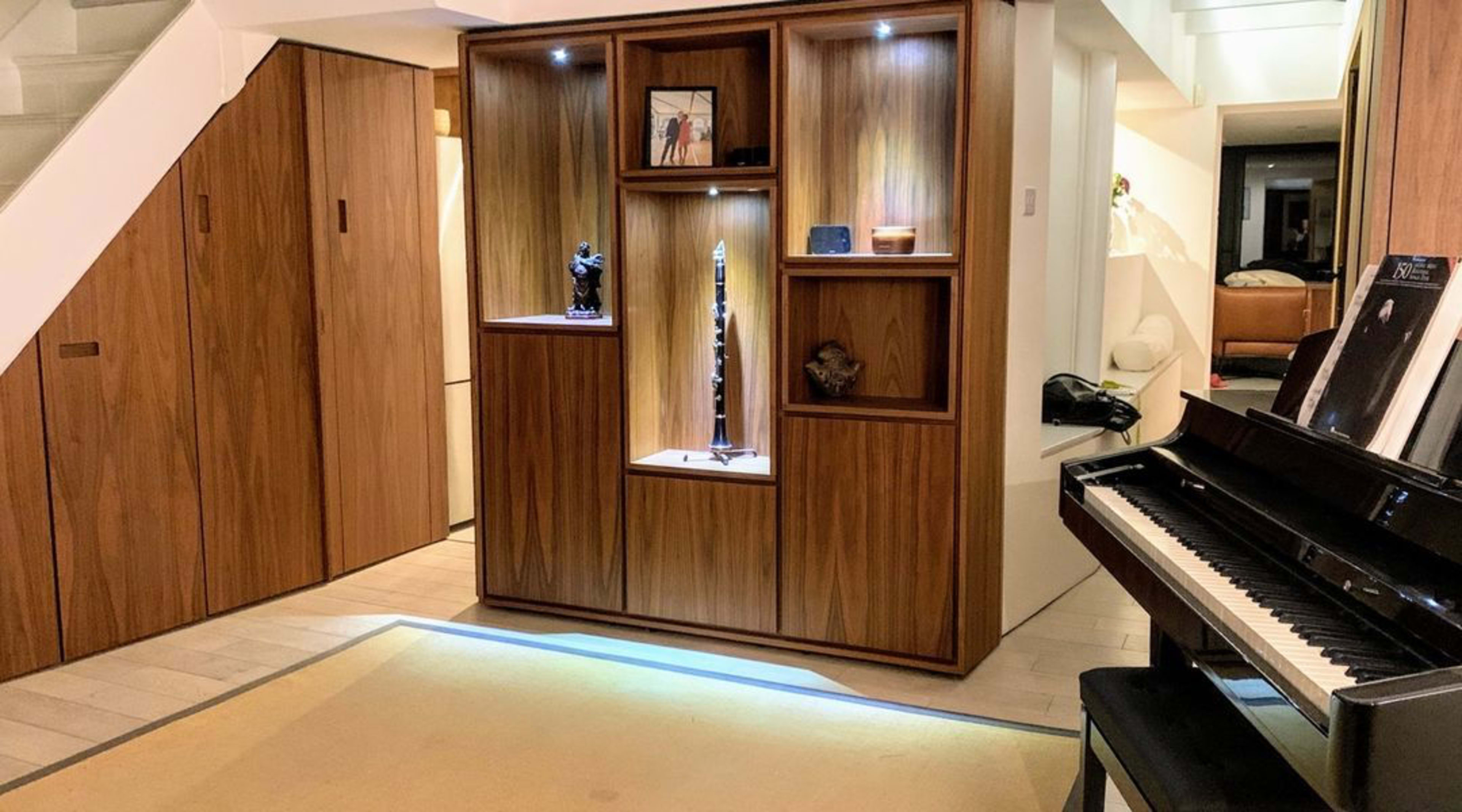 A modern interior space featuring a wooden display cabinet with various decorative items and a piano in the foreground.