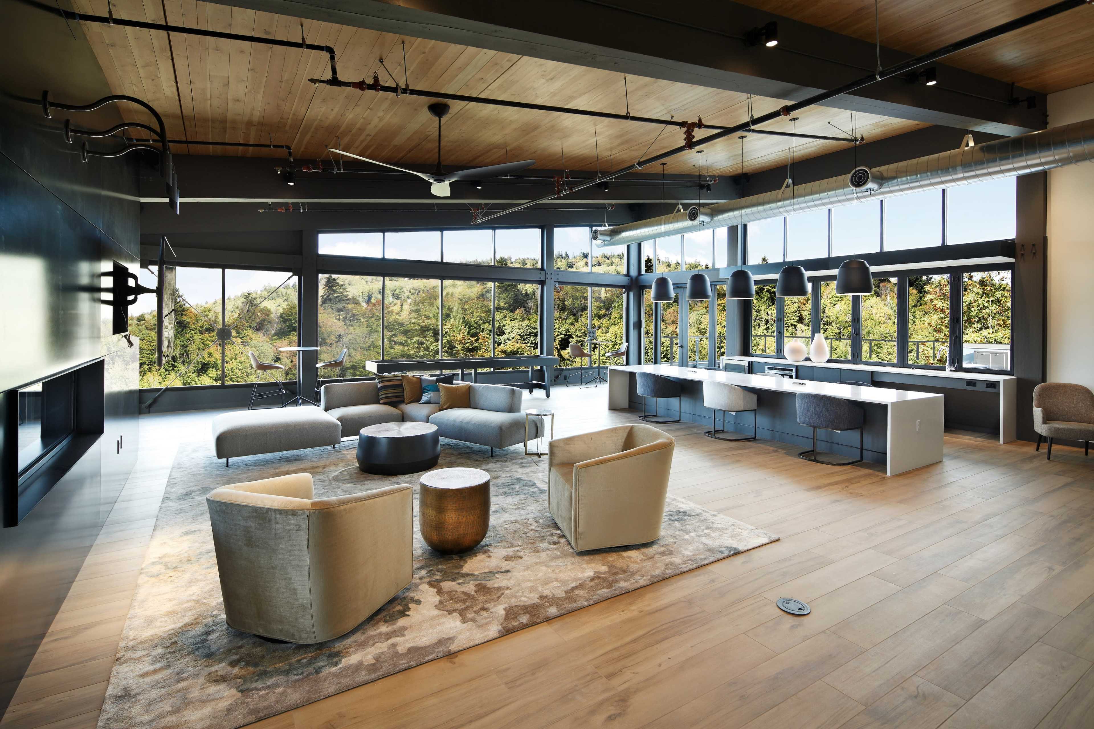 A spacious interior features modern seating arrangements and large windows overlooking a natural landscape.