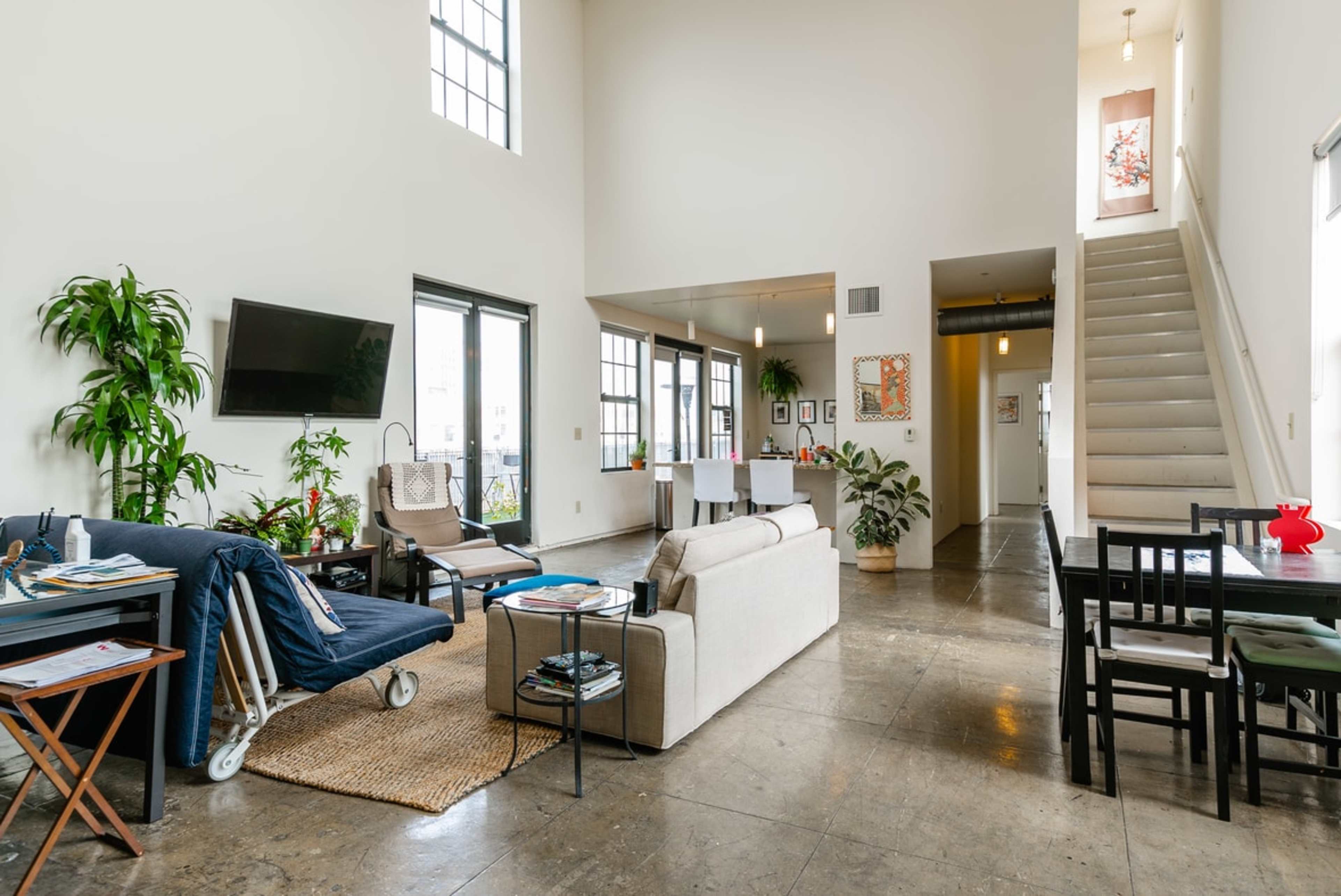 A modern, open-concept living space with a seating area, dining table, and a staircase leading to an upper level.