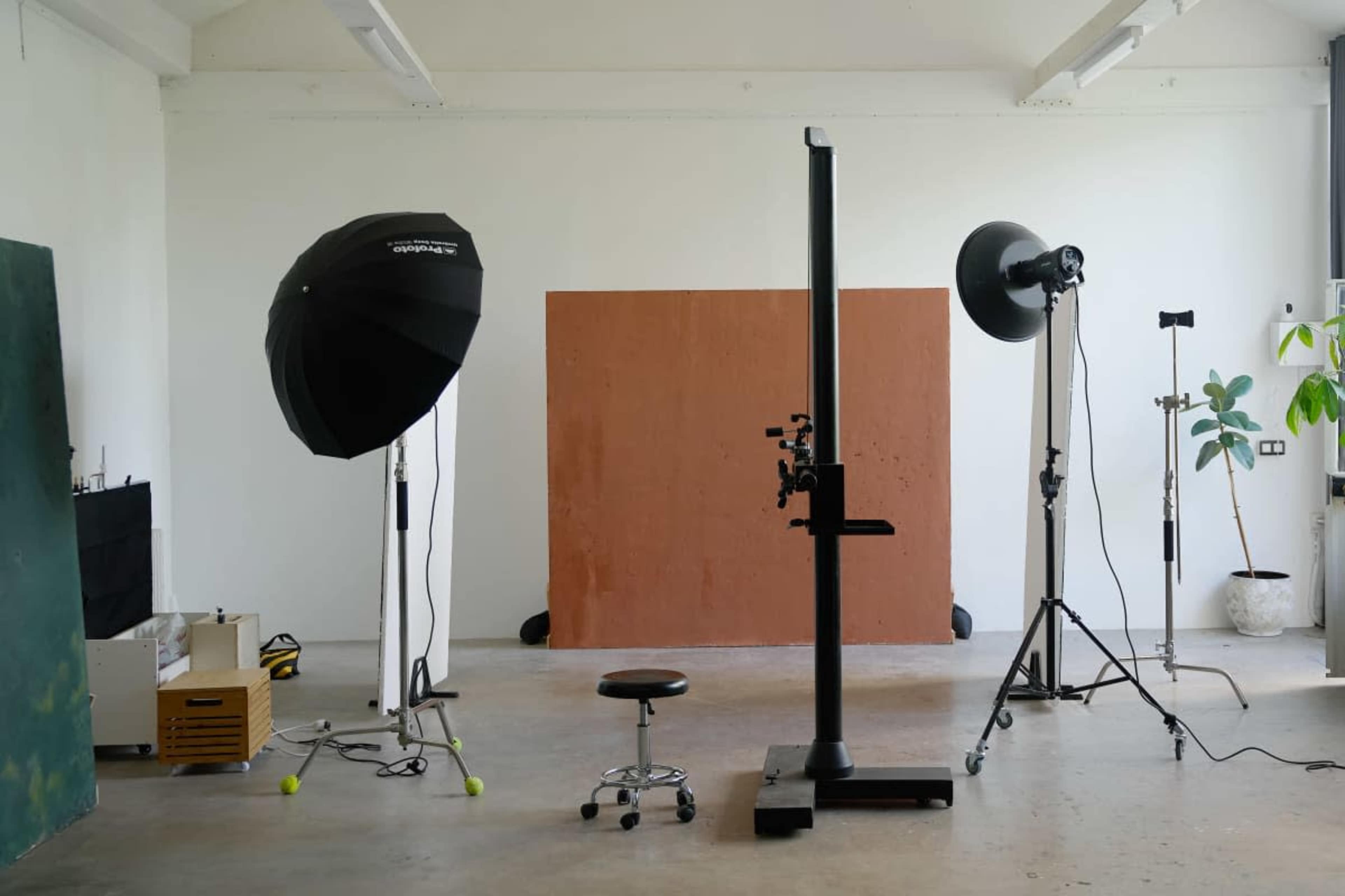 The image shows a photography studio setup with two large softbox lights, a backdrop, and a stool positioned in the center.