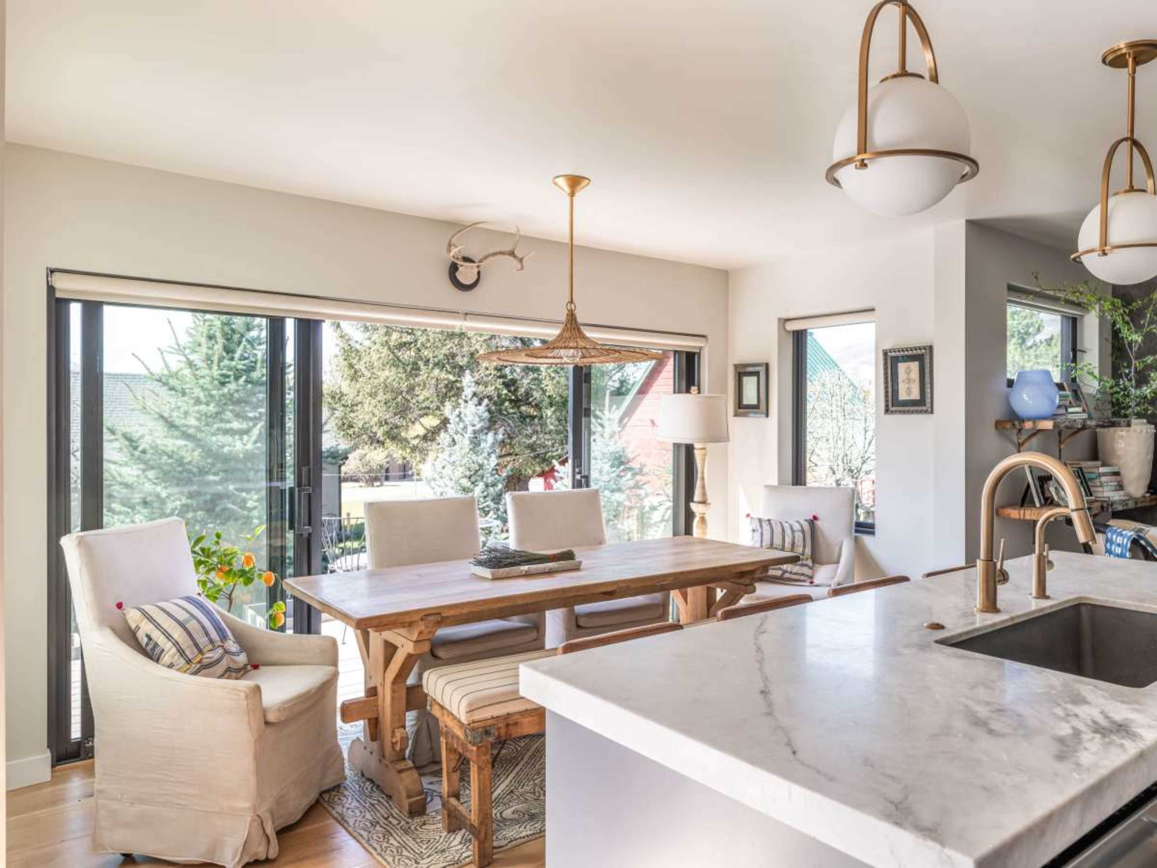 A spacious dining area features a wooden table, comfortable chairs, and large windows allowing natural light to fill the space.