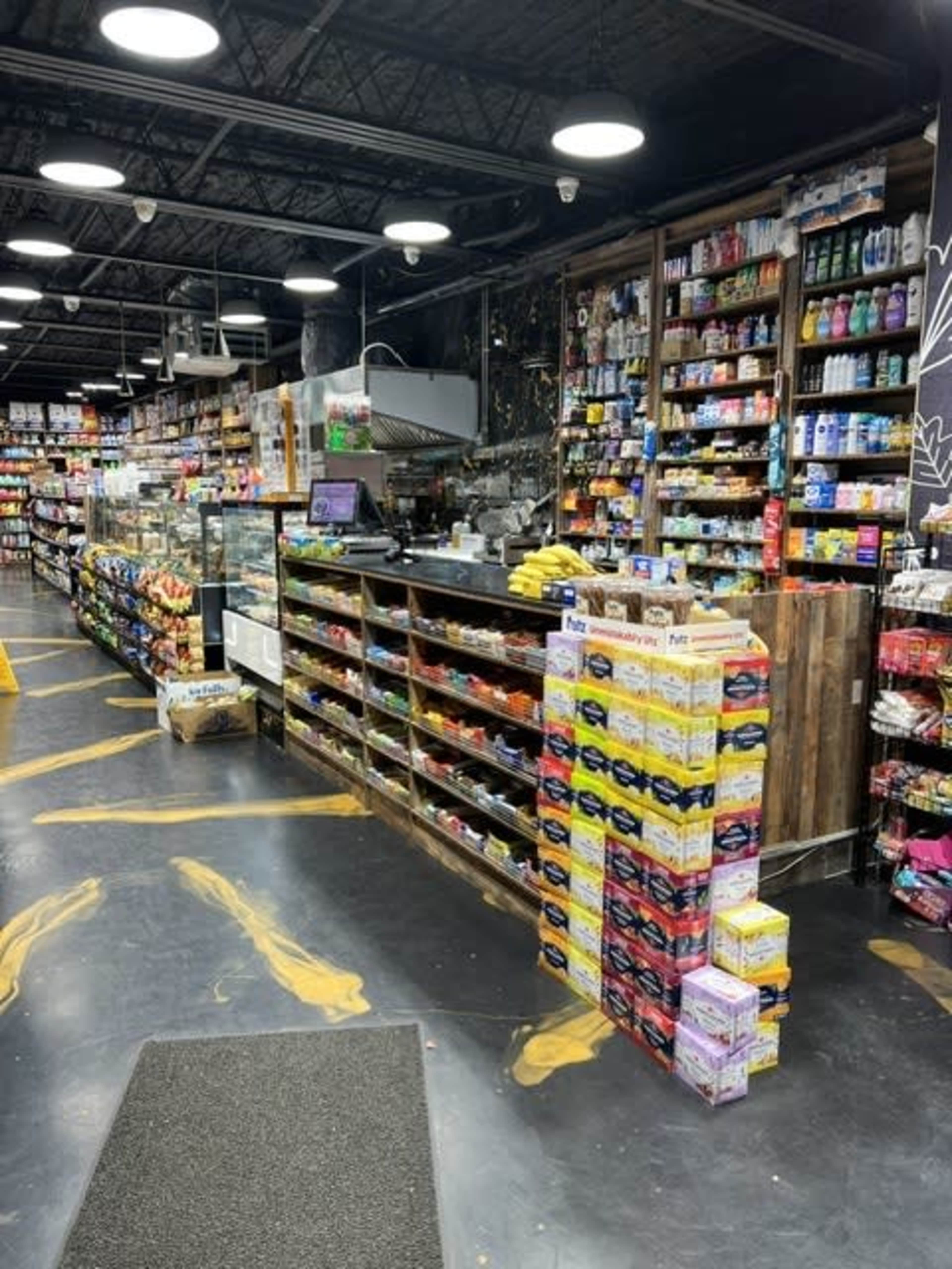 The interior of a convenience store with a checkout counter and shelves stocked with various products.