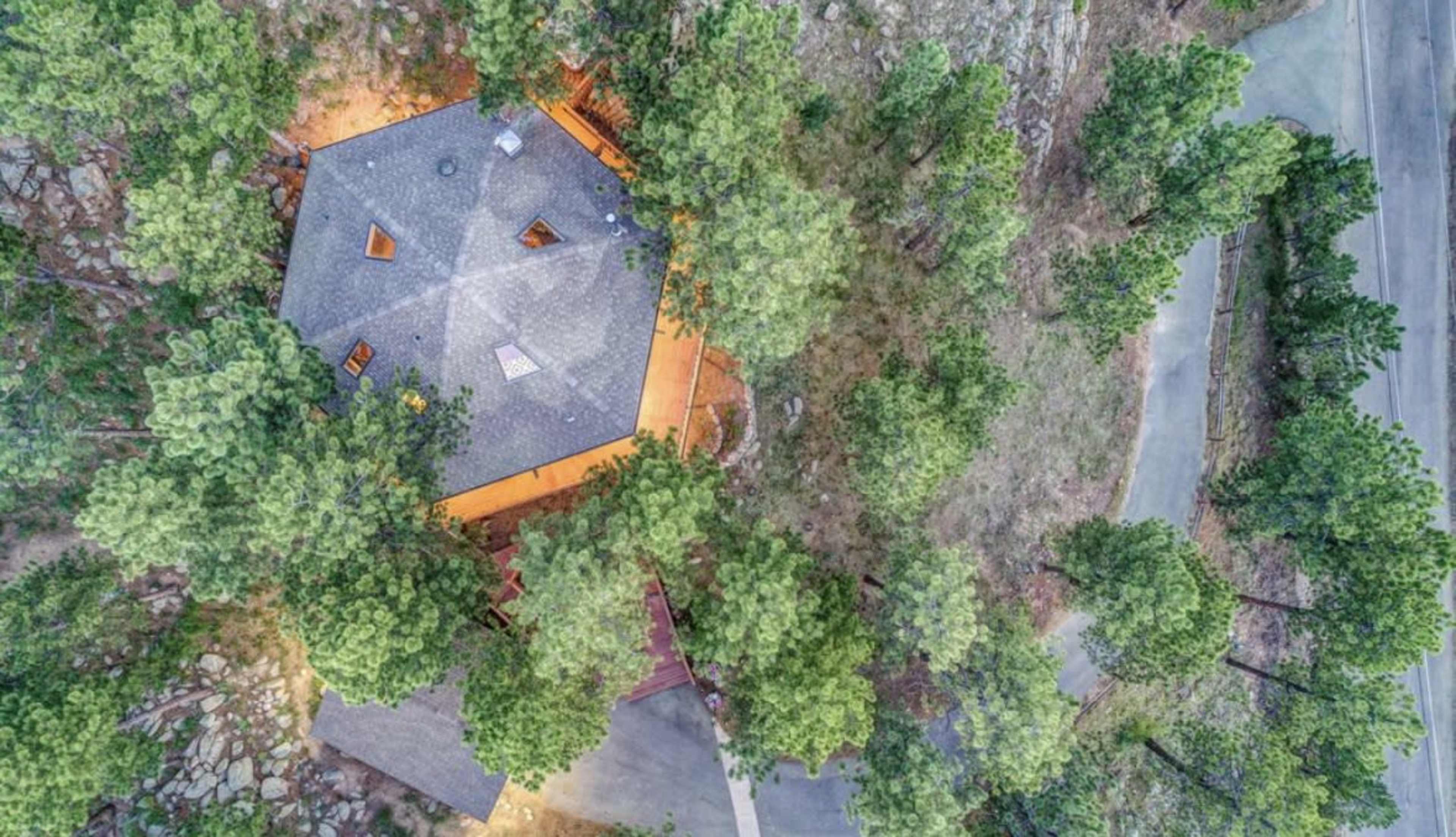 An aerial view of an octagonal building surrounded by trees and a winding road.