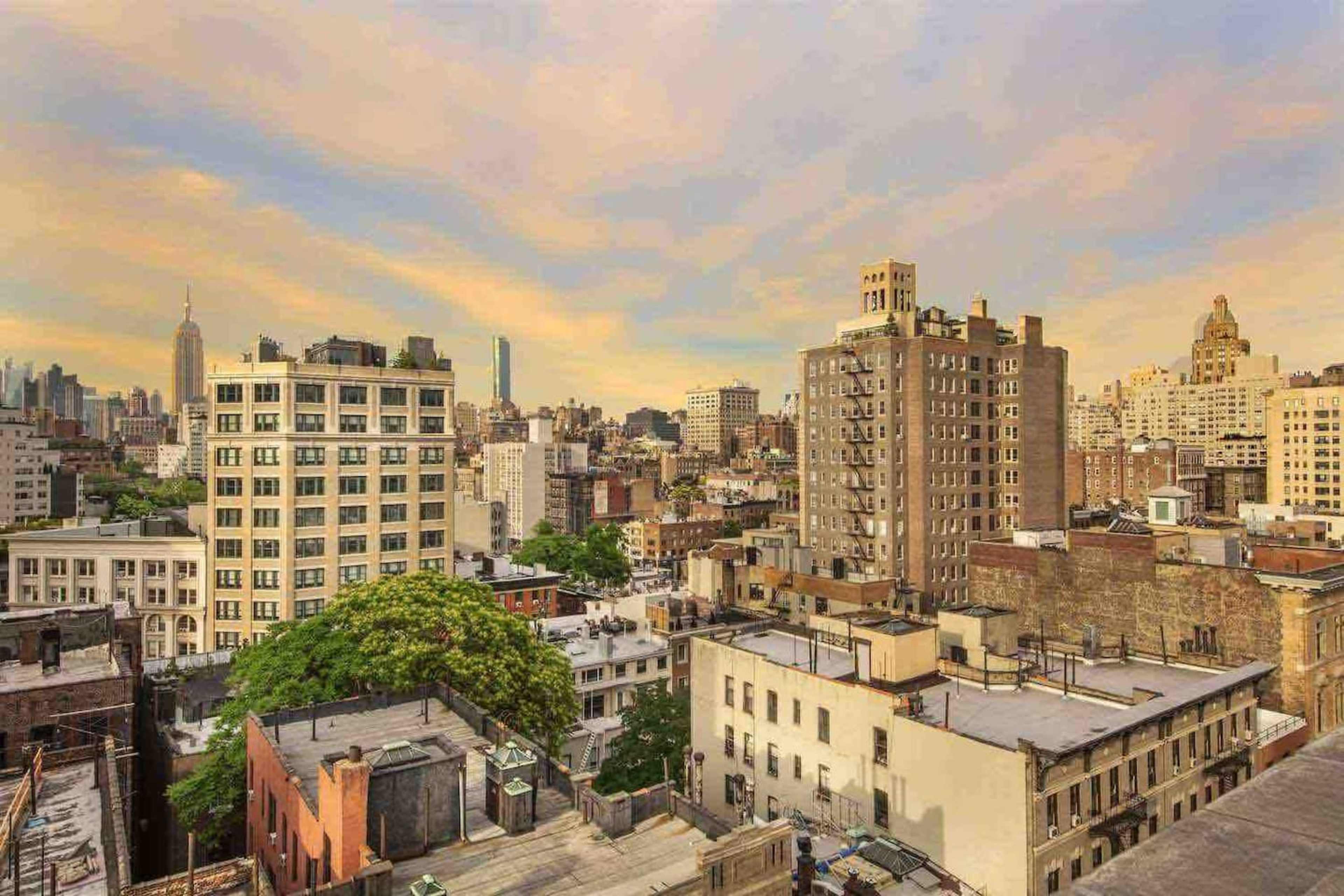 The image shows a panoramic view of a city skyline featuring various buildings and skyscrapers under a colorful sky at dusk.