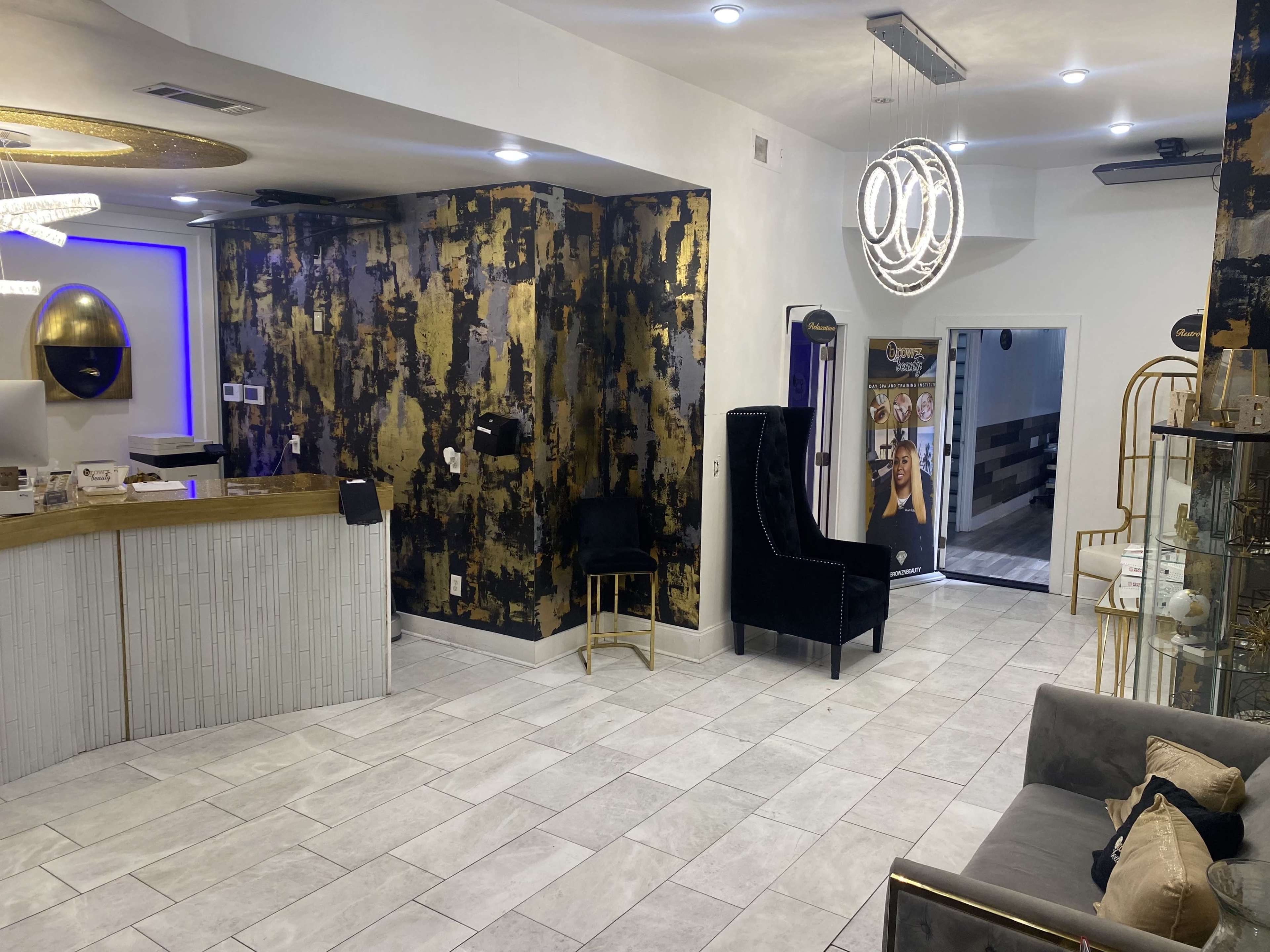 A well-lit reception area with a modern design featuring a gold and black accent wall, a front desk, and seating arrangements.