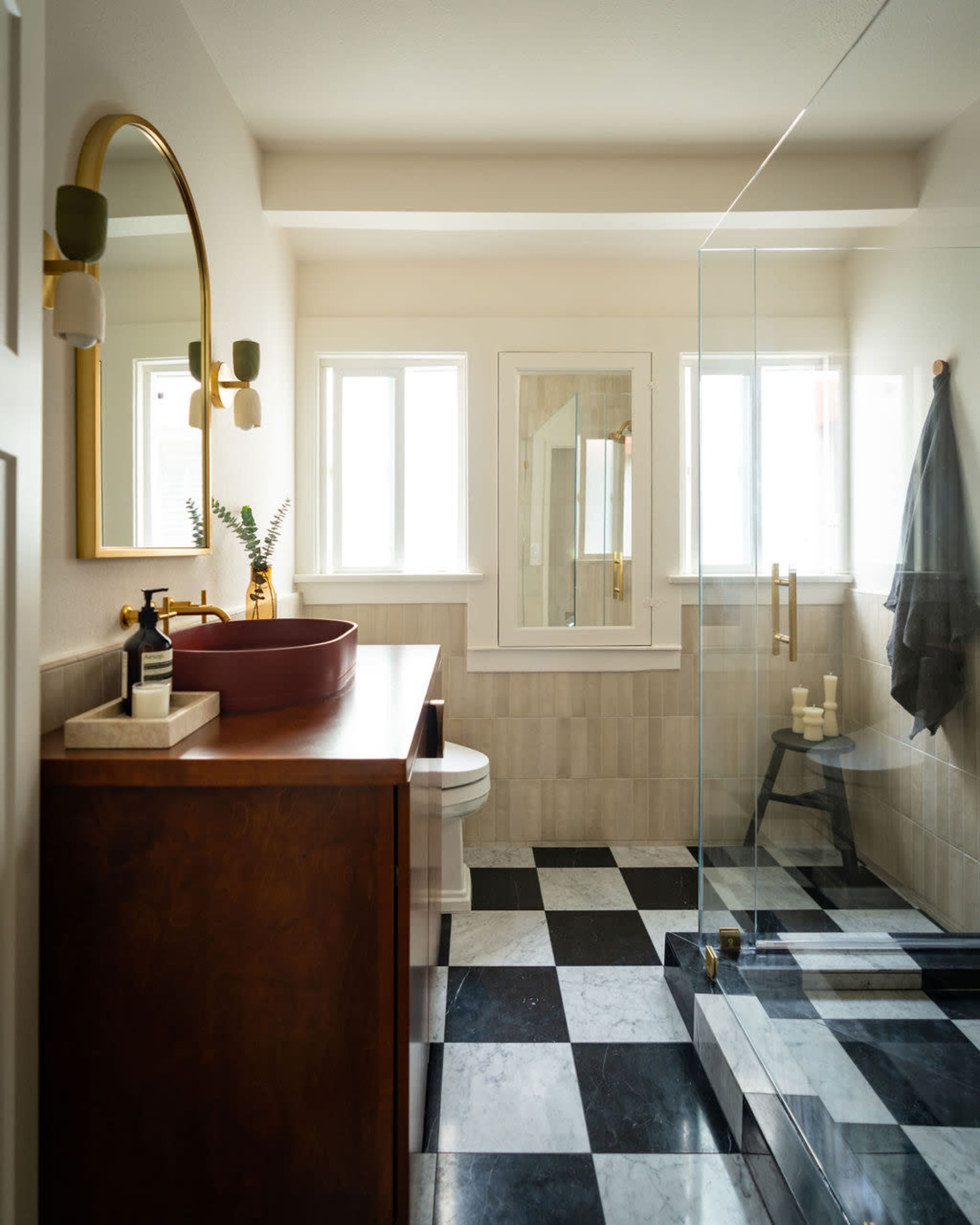 The bathroom features a modern design with a freestanding vanity, a glass shower enclosure, and a checkered black-and-white floor.