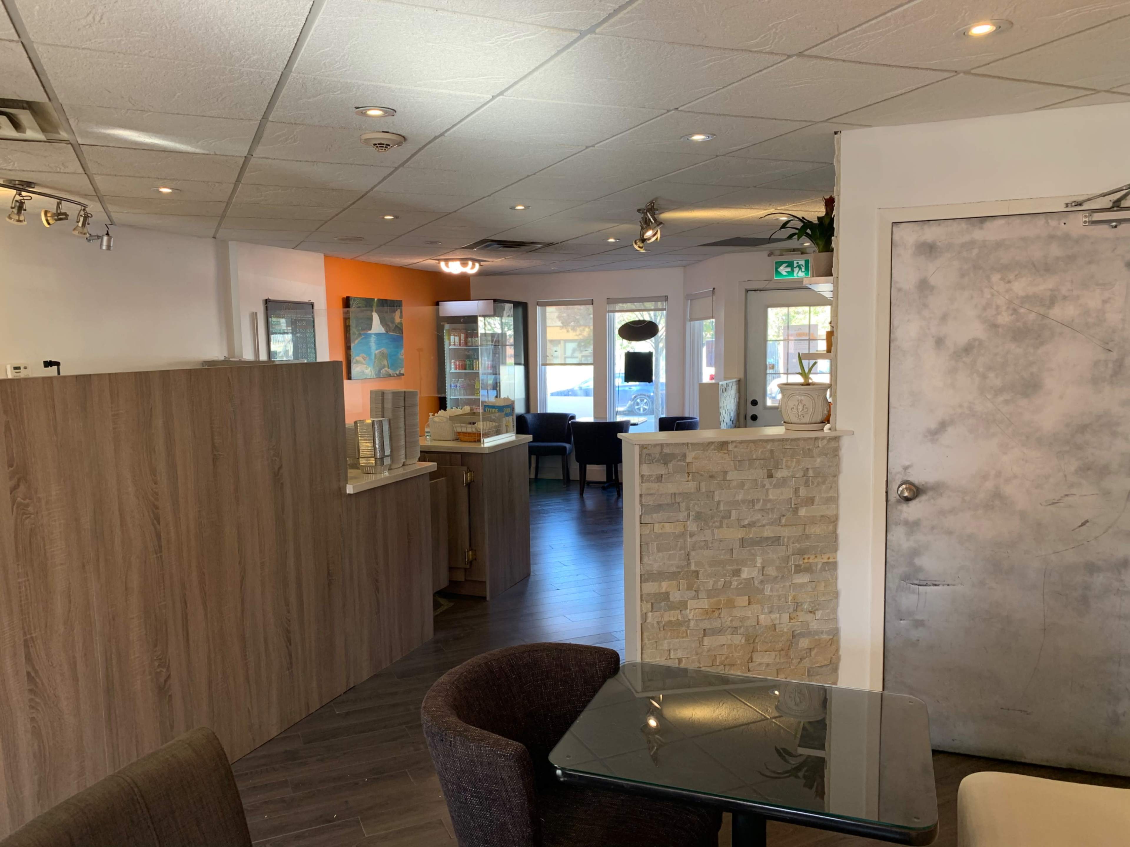 The interior of a café or restaurant featuring wooden paneling, a stone accent wall, and seating areas with tables and chairs.
