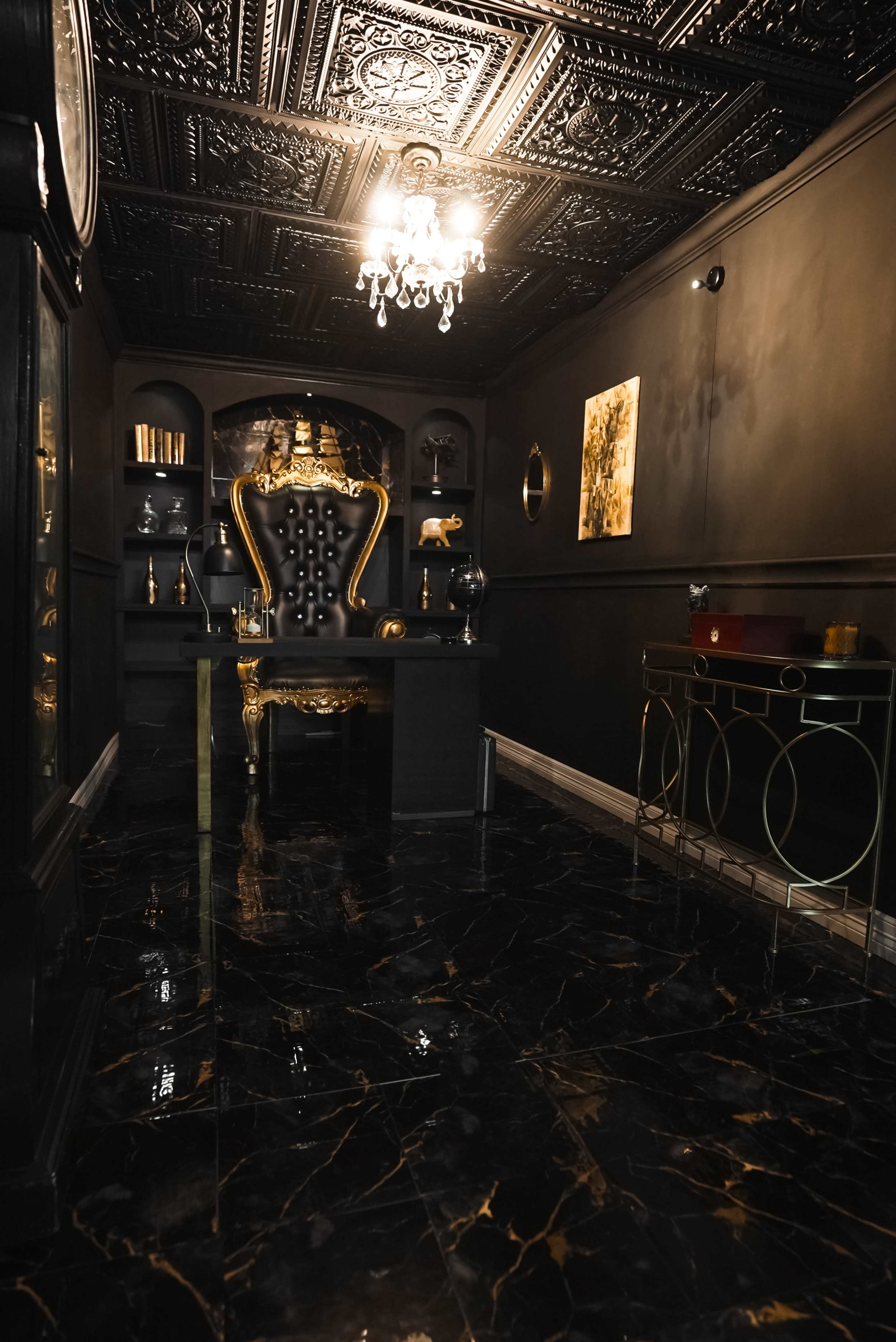 The image features a dark, elegantly designed room with a plush, high-backed chair, a marble floor, and ornate ceiling details.