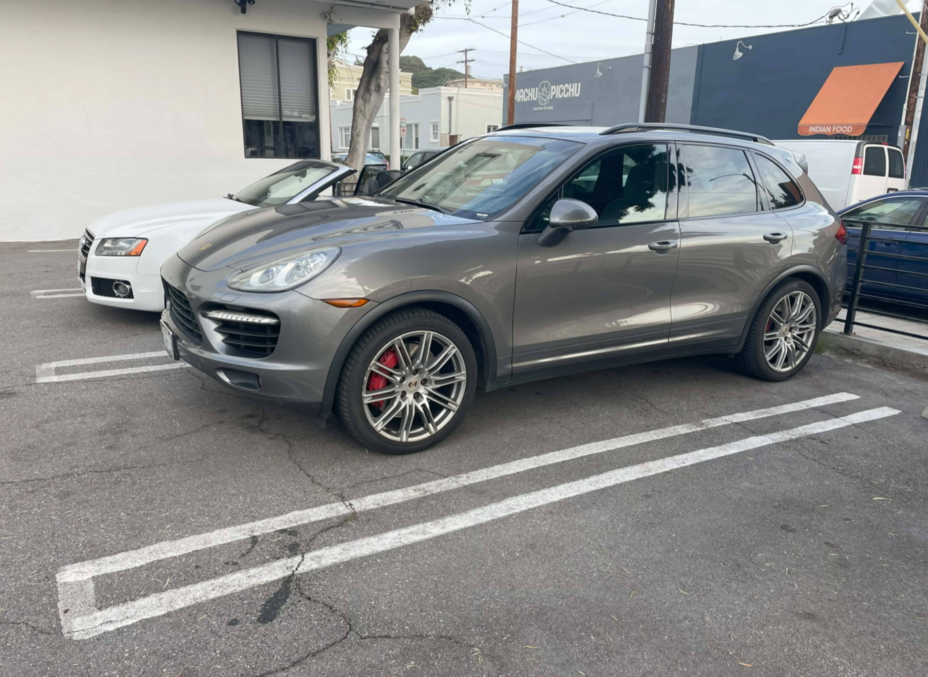 A gray SUV is parked in a parking lot next to a white sedan.