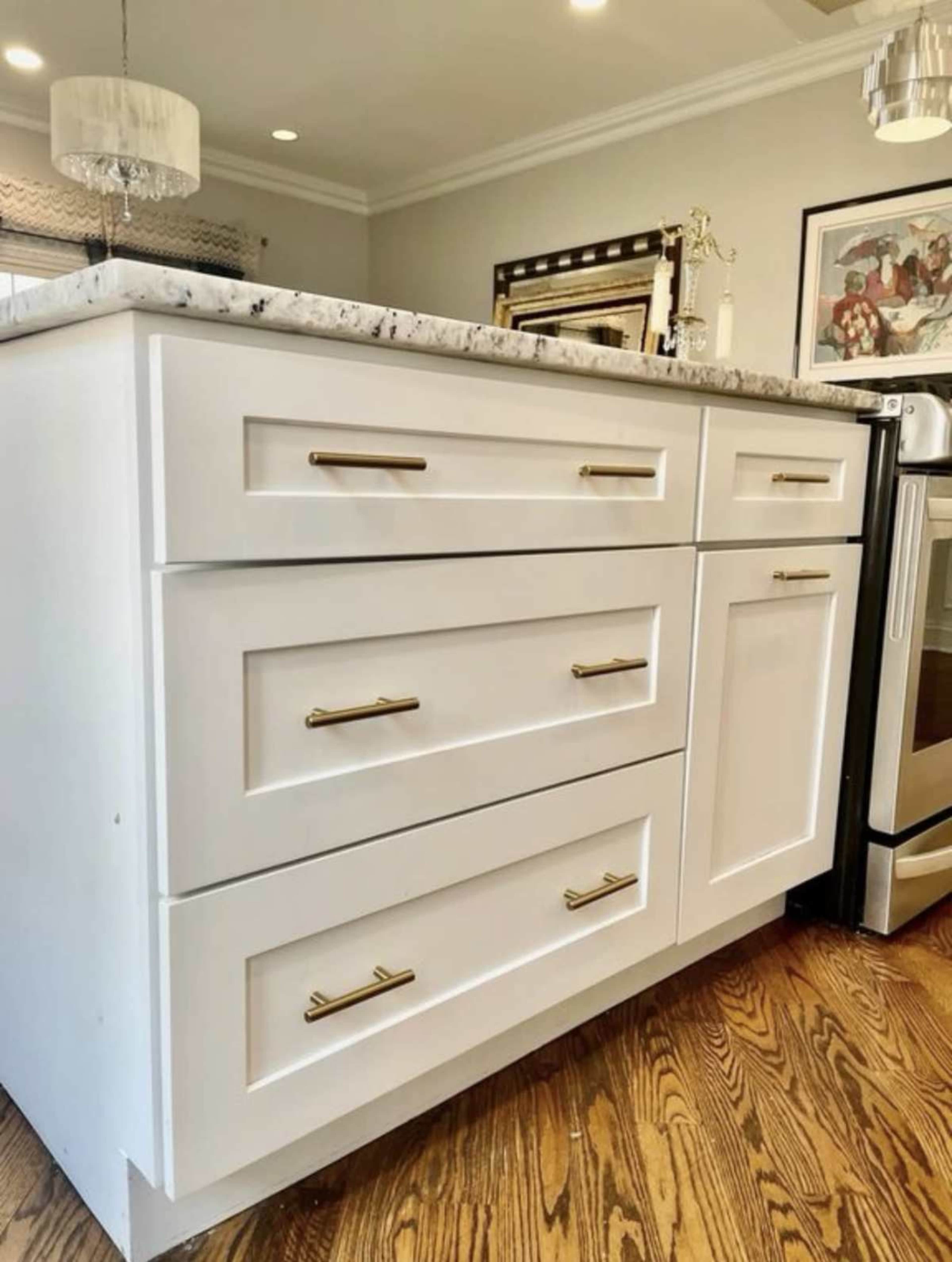 A white kitchen island with four drawers and a countertop made of marble.