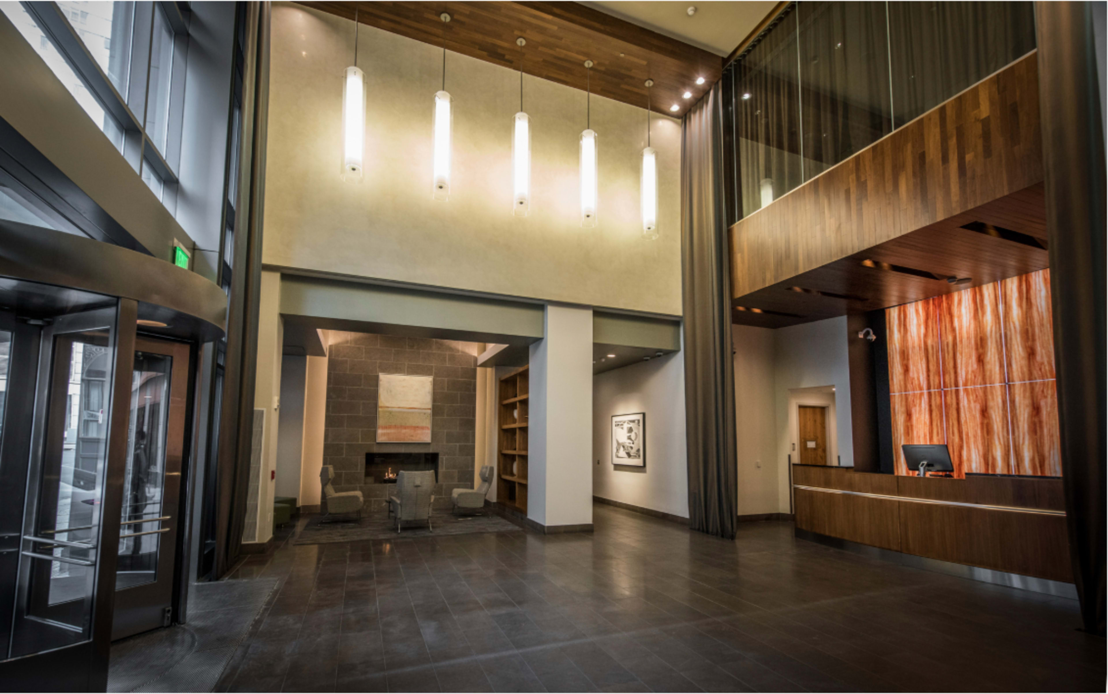 The lobby features a stone fireplace, modern seating, and a reception desk with pendant lighting above.