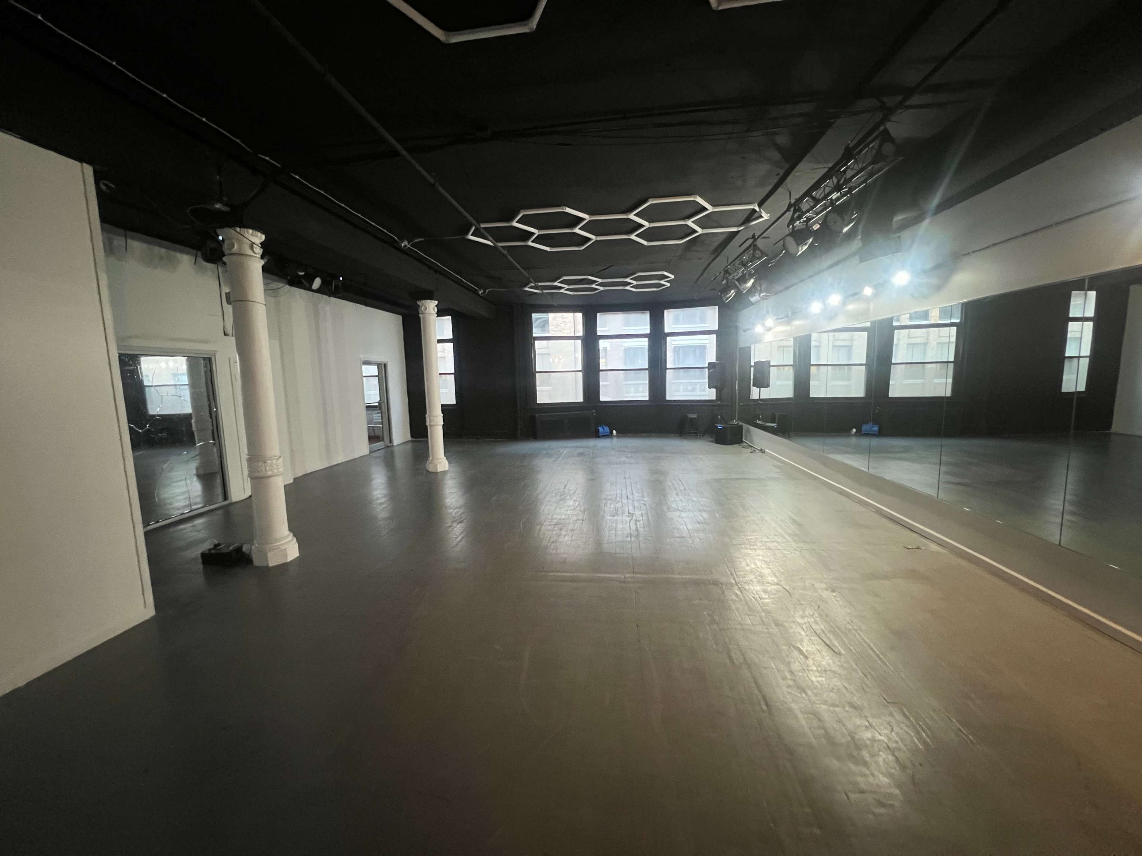The image shows a spacious, well-lit interior of a dance studio with polished floors and mirrored walls.