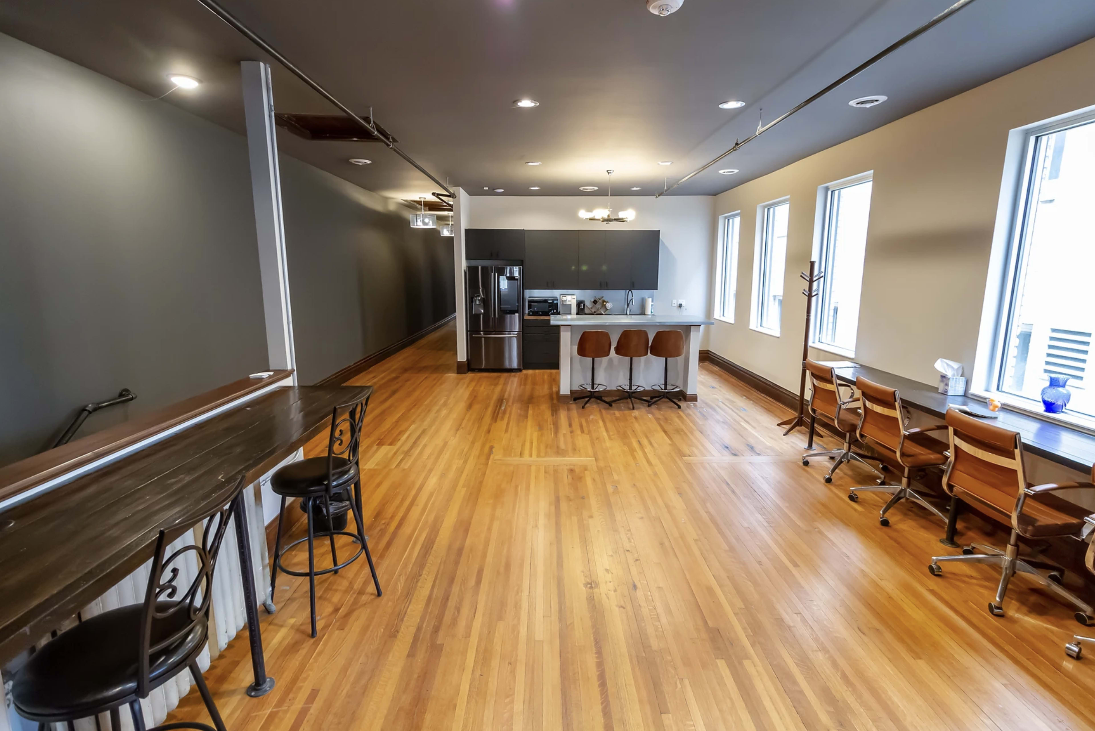 A spacious, modern open-plan kitchen and dining area with hardwood floors and large windows.
