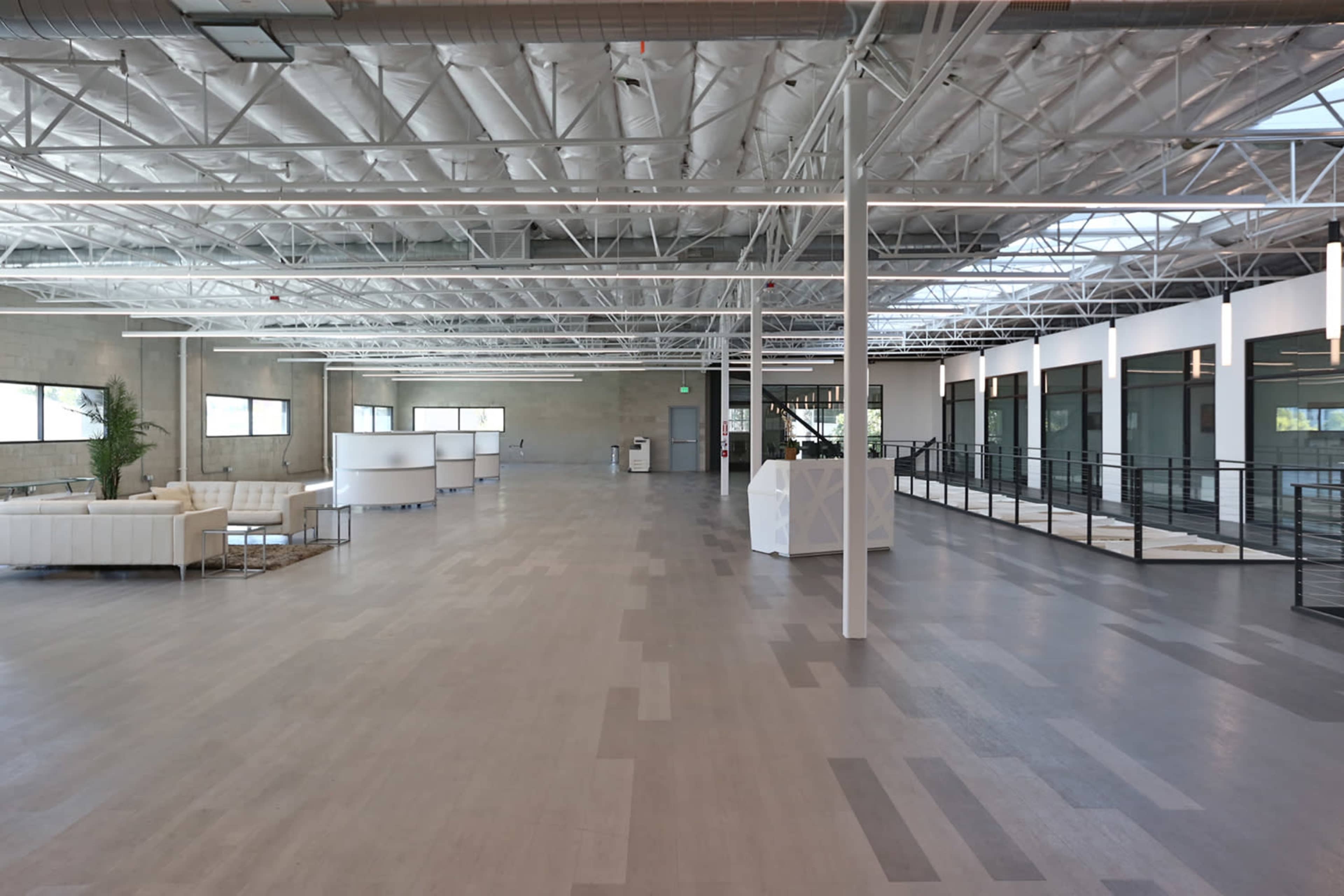 A spacious, modern interior of an office facility with high ceilings, large windows, and minimalist furniture.