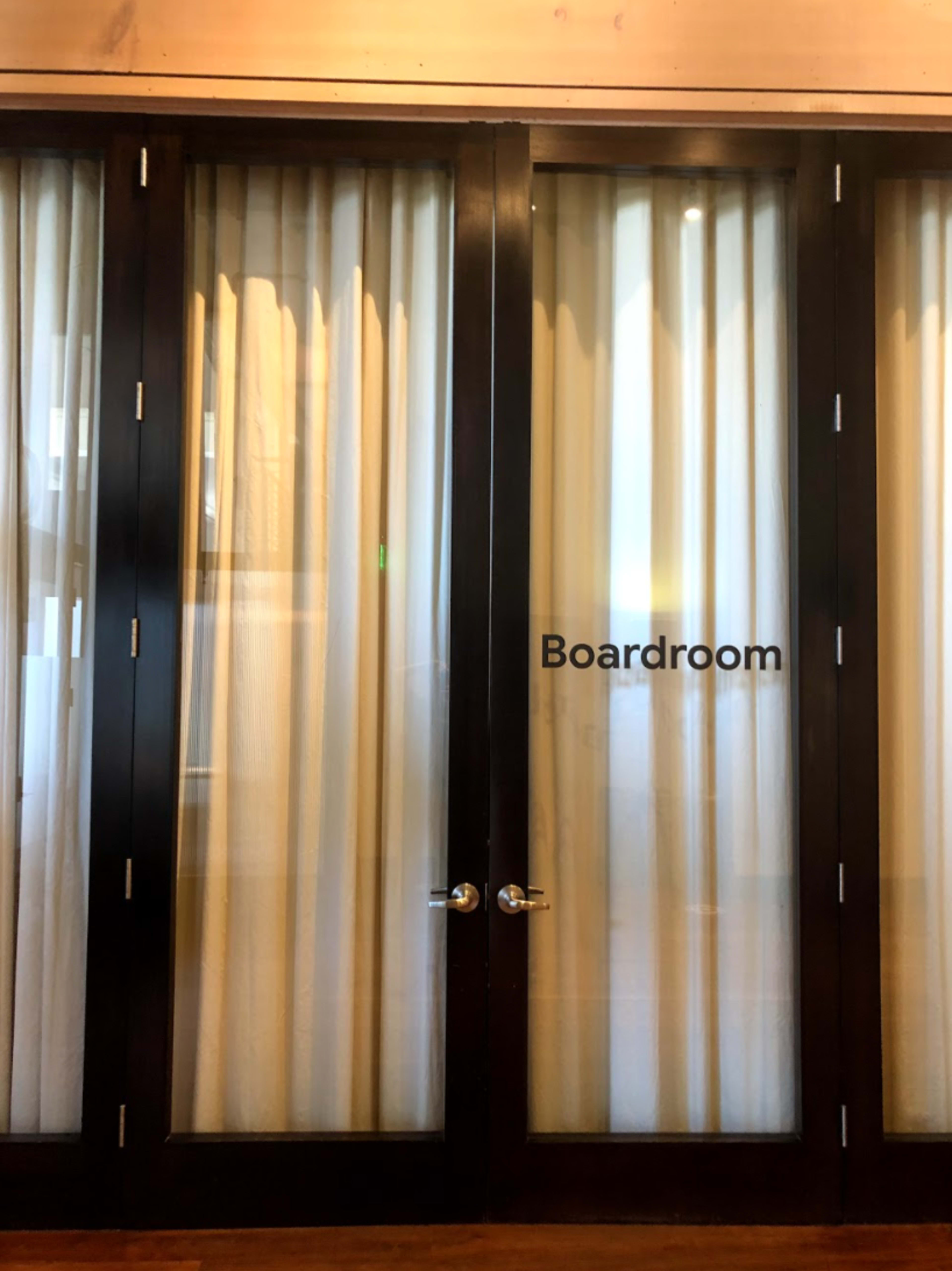A set of glass doors with sheer curtains and a label that reads "Boardroom."