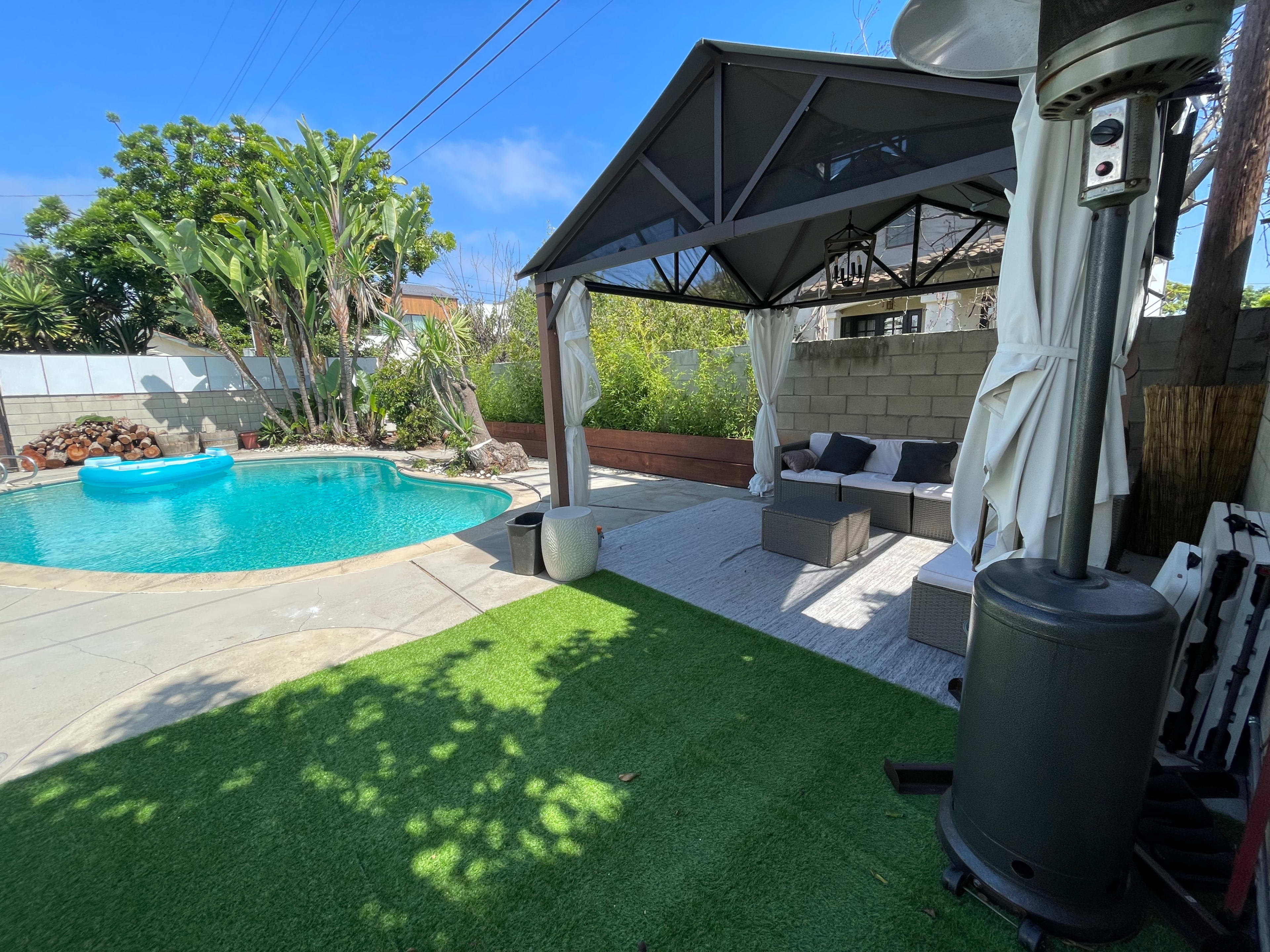 A patio area features a gazebo with seating, a swimming pool, and landscaped greenery.