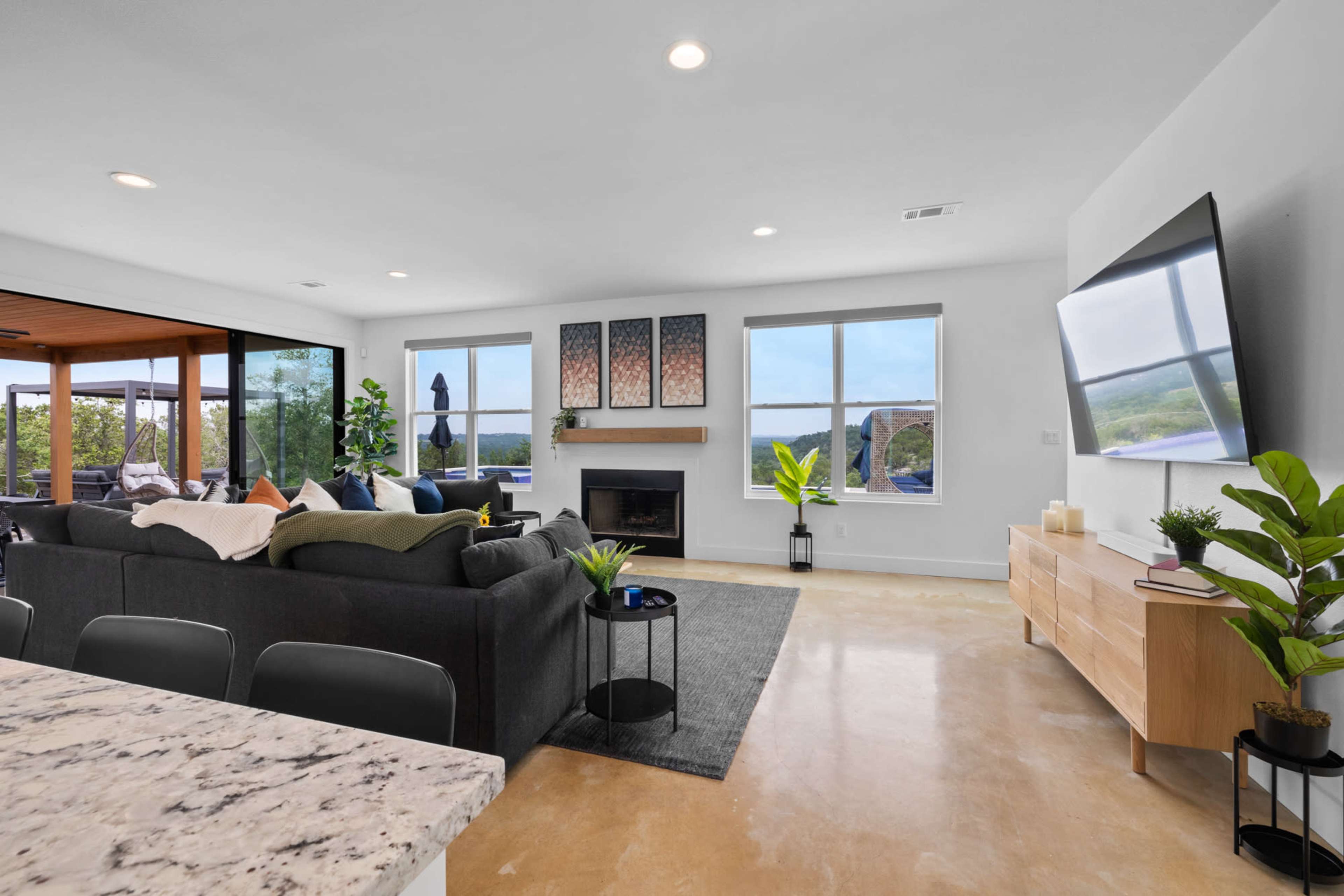 A modern living room with a gray sectional sofa, a coffee table, and large windows overlooking a scenic view.