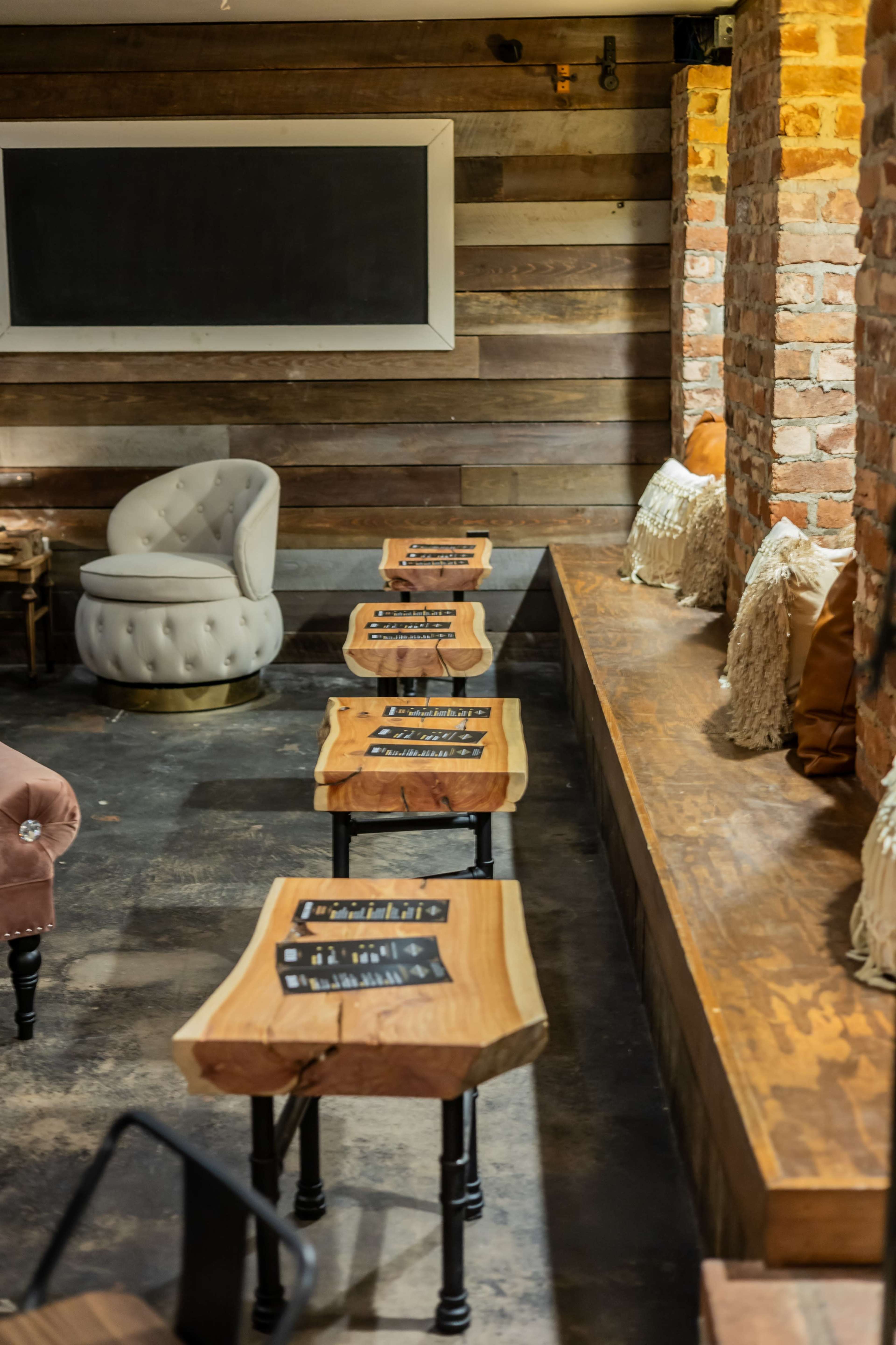 The image shows a rustic interior of a café with wooden tables and benches against a brick wall.