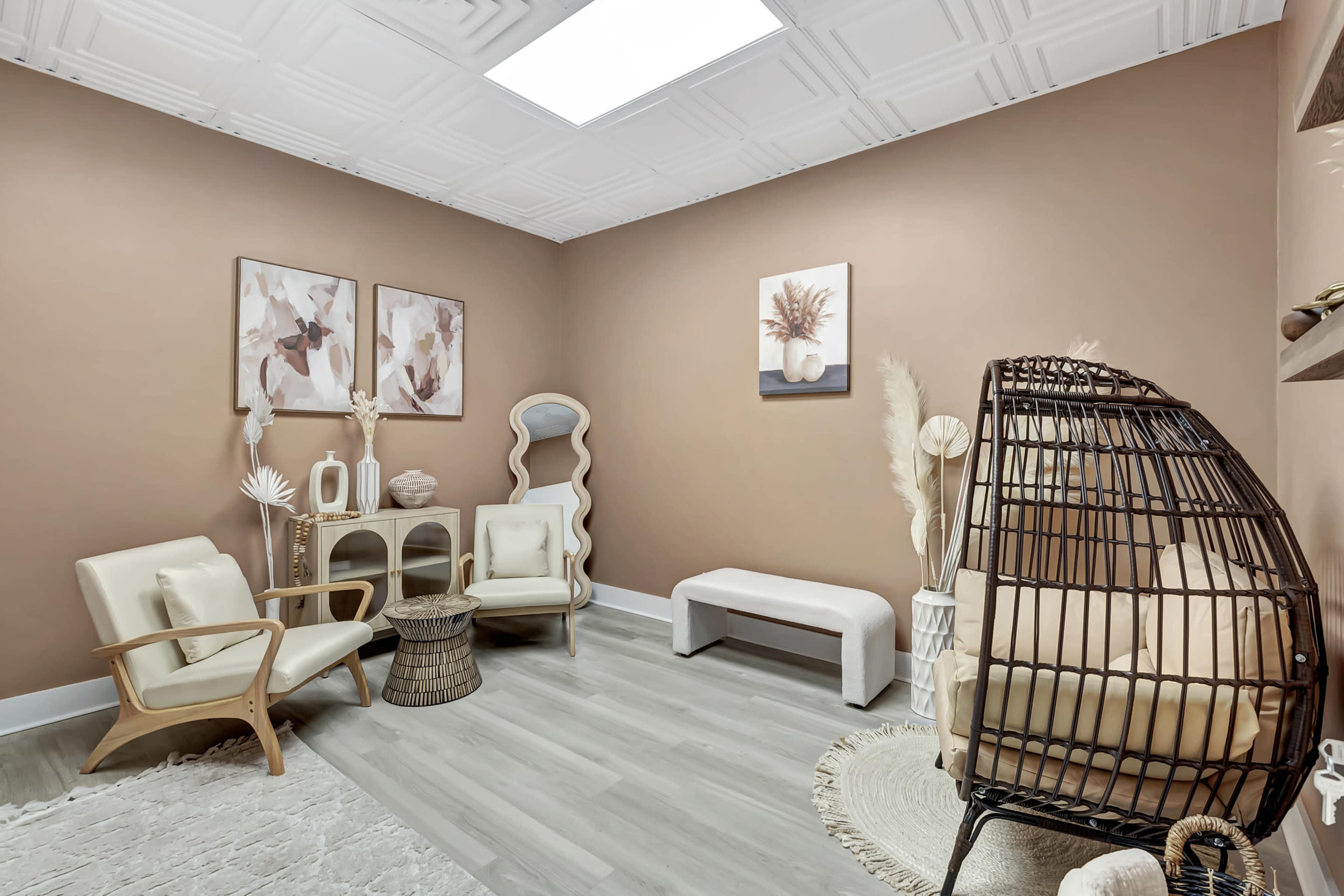 A cozy waiting room with neutral-toned walls, vintage-style furniture, and decorative plants arranged in a modern layout.