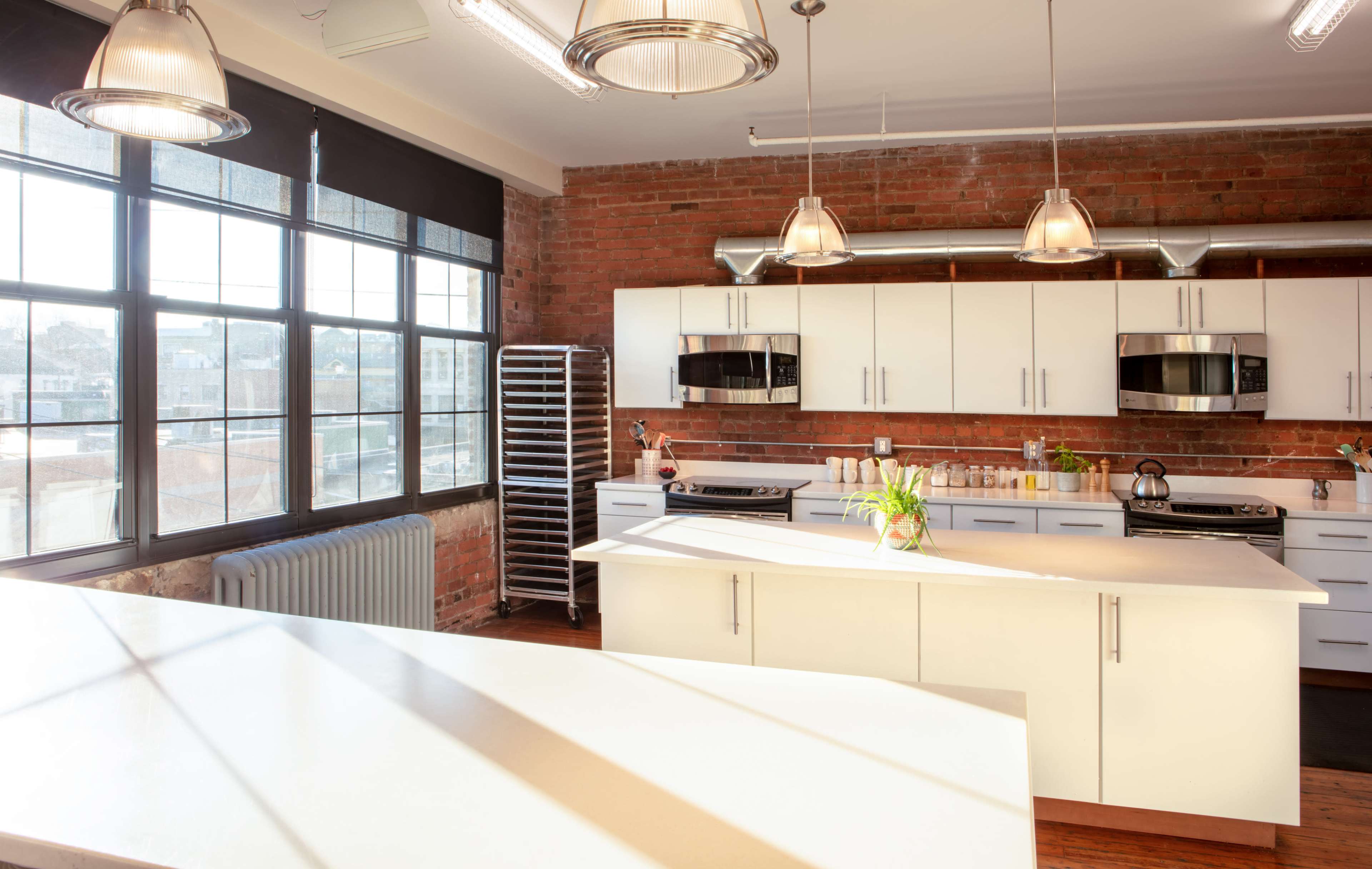A modern kitchen features white cabinets, stainless steel appliances, and large windows with a view of the city.