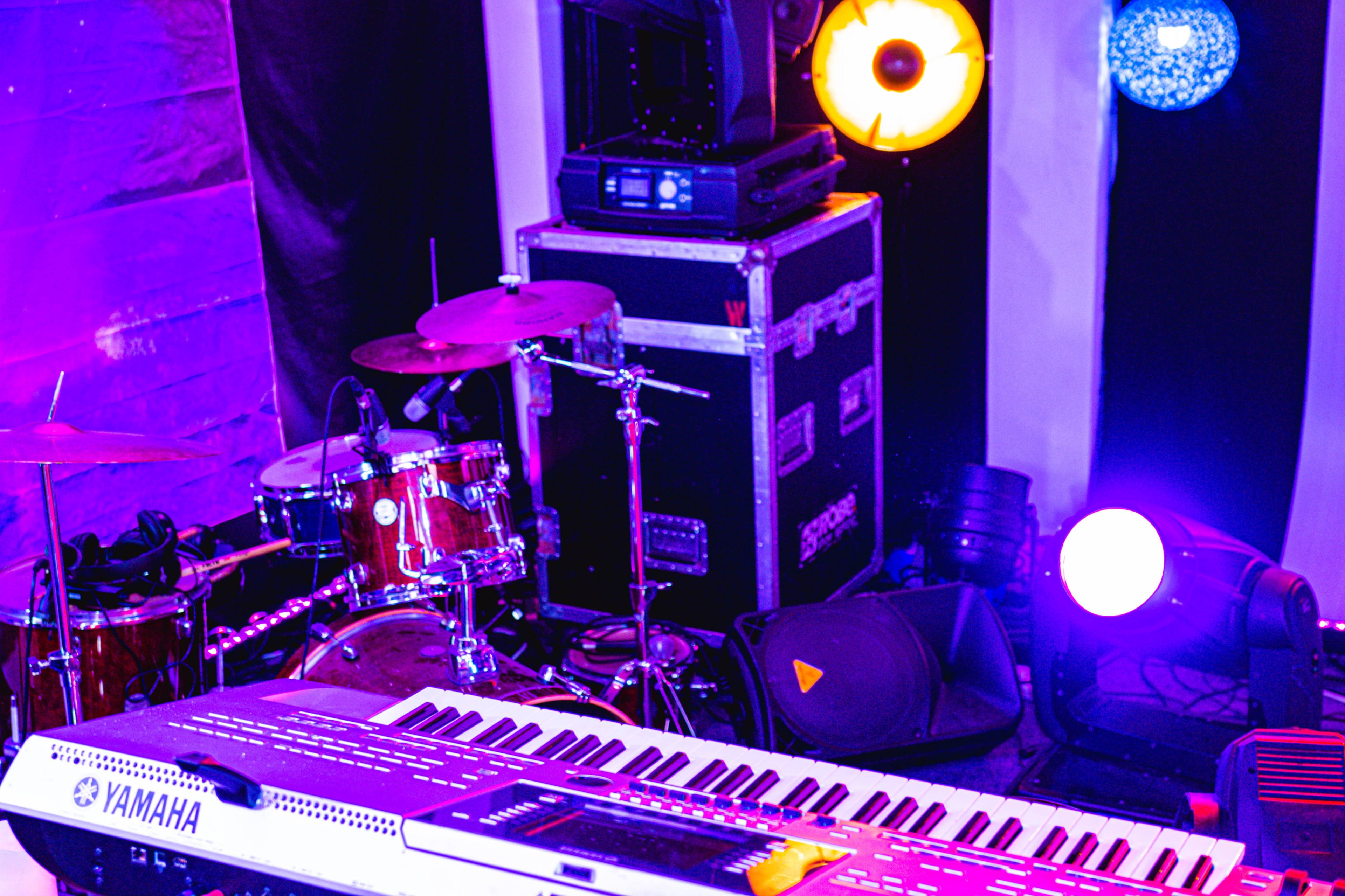 A stage setup featuring a keyboard, a drum kit, and various stage lights.