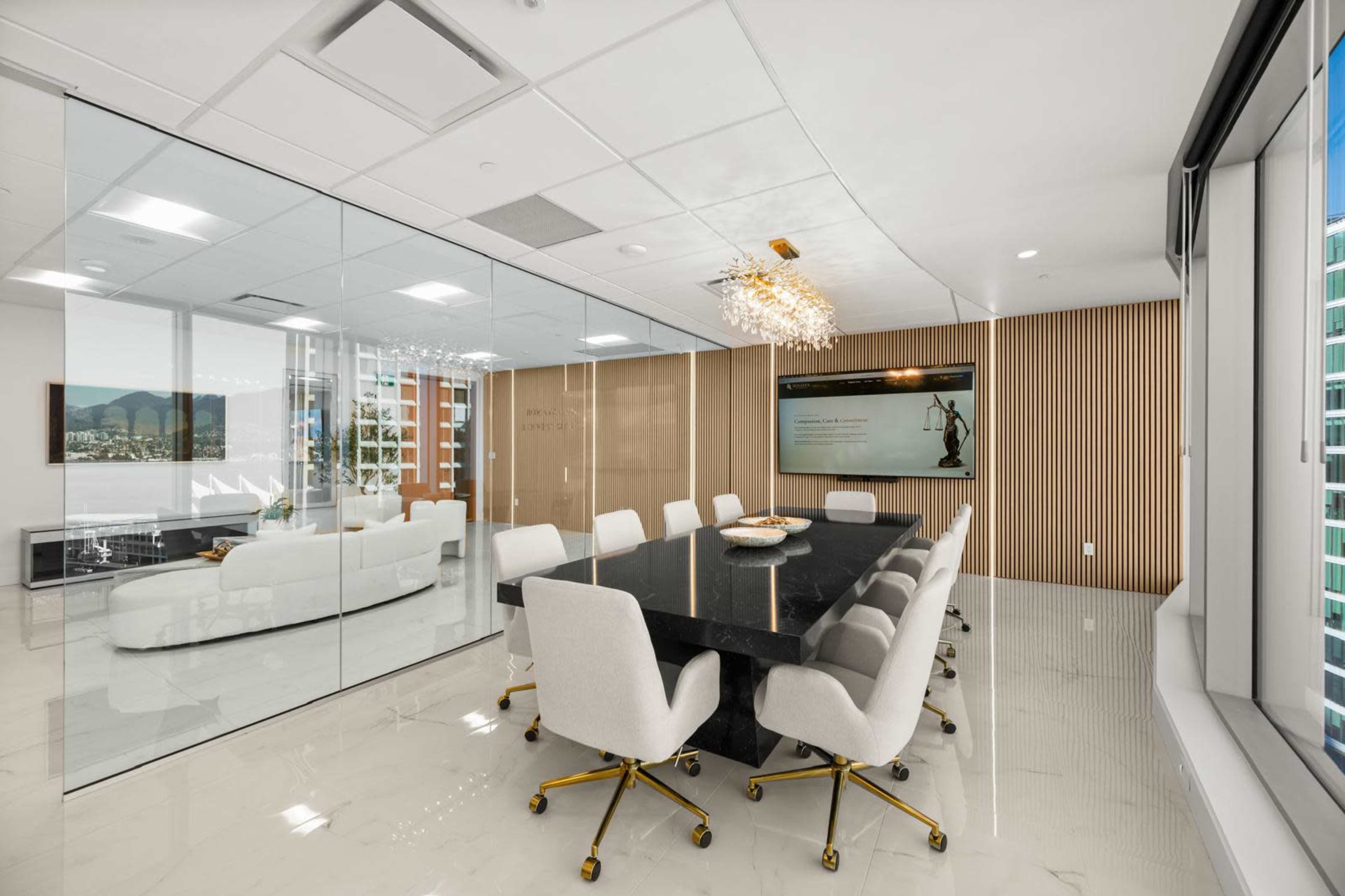 A modern conference room features a large black table surrounded by white chairs and glass walls, with a city view visible through the windows.