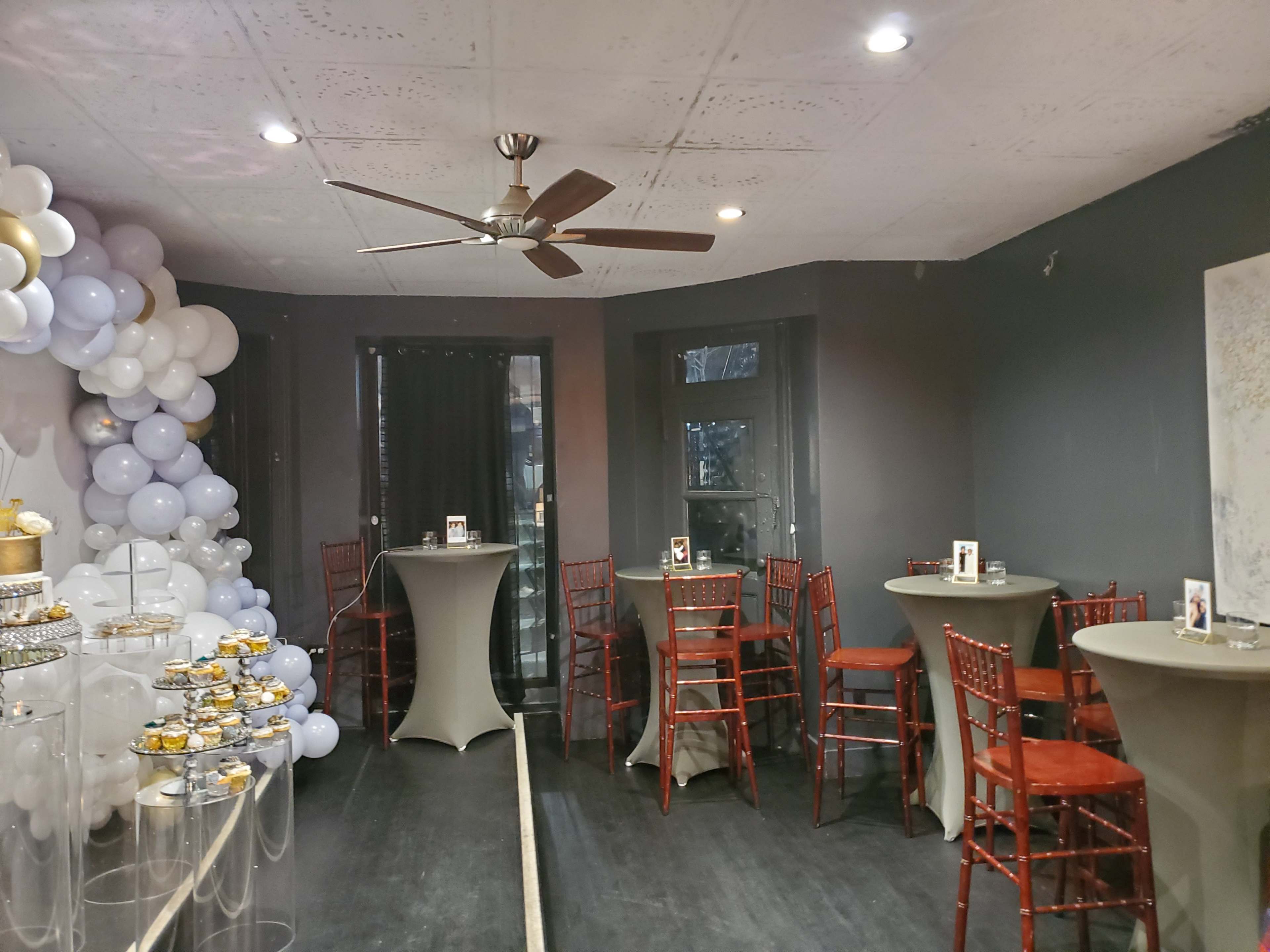 A decorated event space with tables, chairs, and a balloon display.