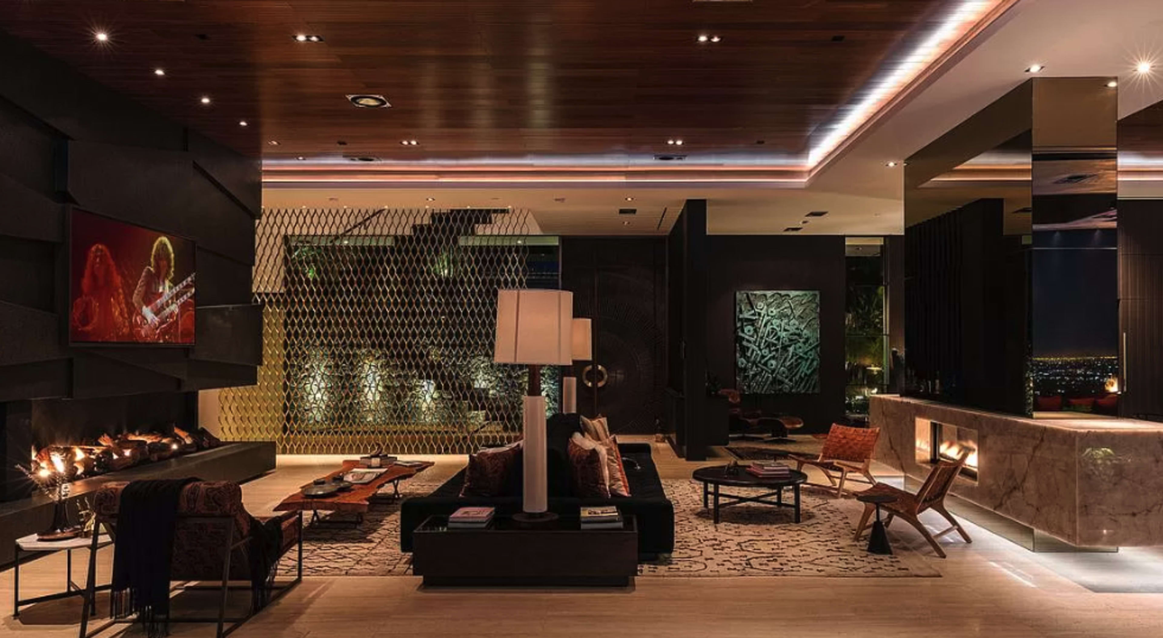 The image shows a modern and stylish hotel lobby featuring a dark color palette, comfortable seating arrangements, ambient lighting, and a sleek reception area with a large marble counter.