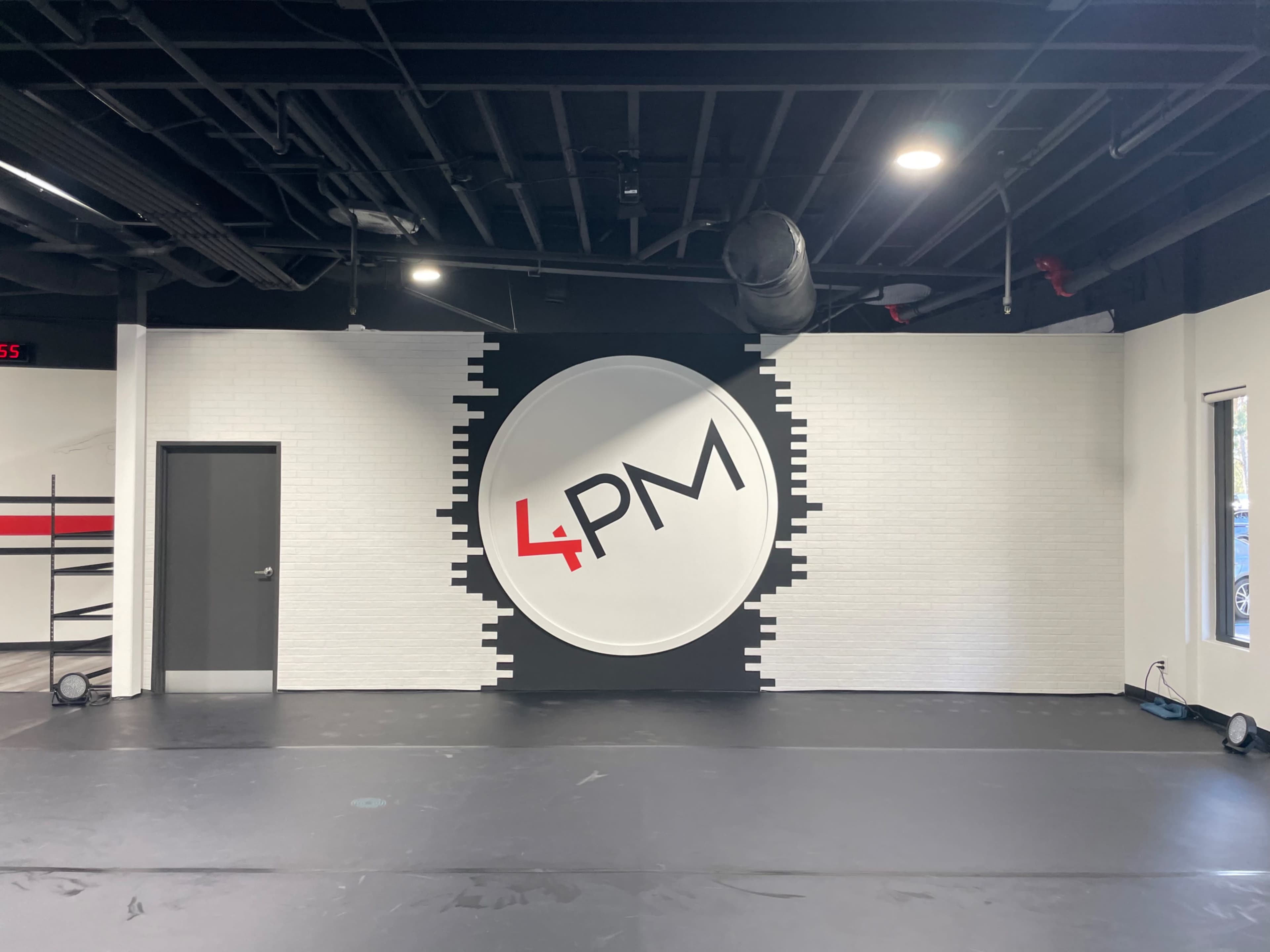 A spacious interior with a large clock-themed mural displaying "4 PM" on a black and white wall.