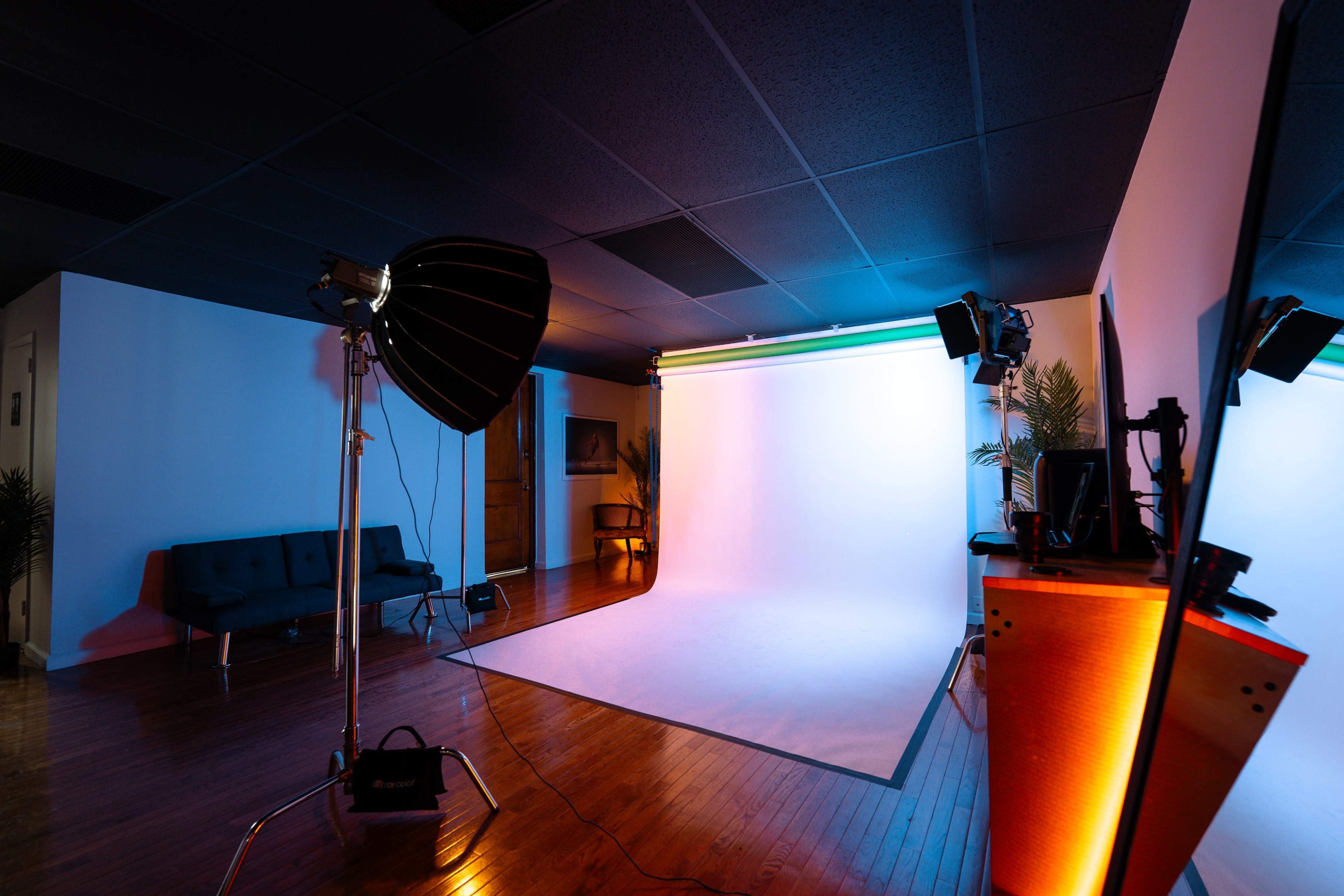 A photography studio features a backdrop with lighting equipment and furniture arranged in the space.