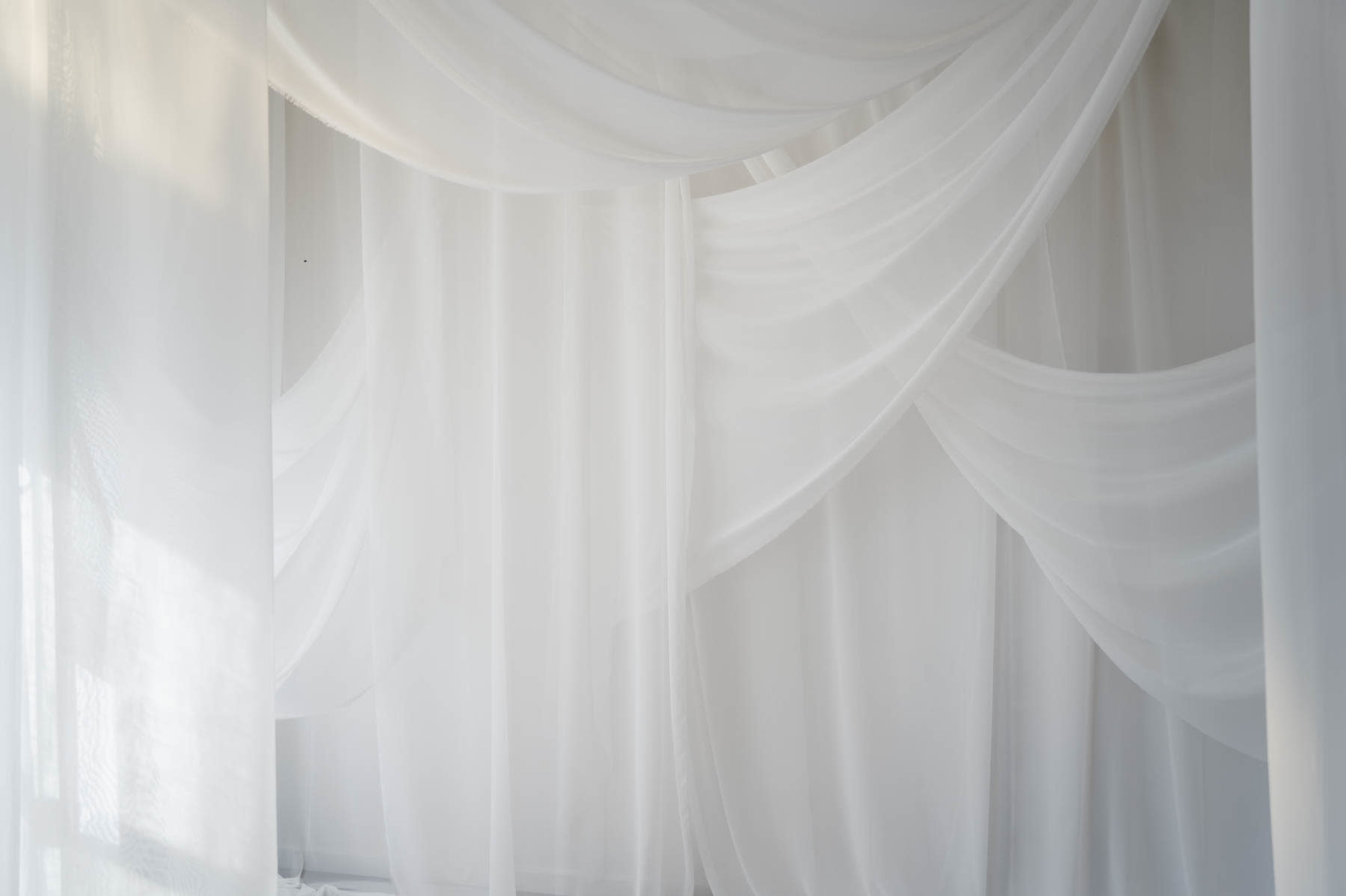 The image shows a softly draped arrangement of sheer white fabric creating a serene and airy atmosphere.