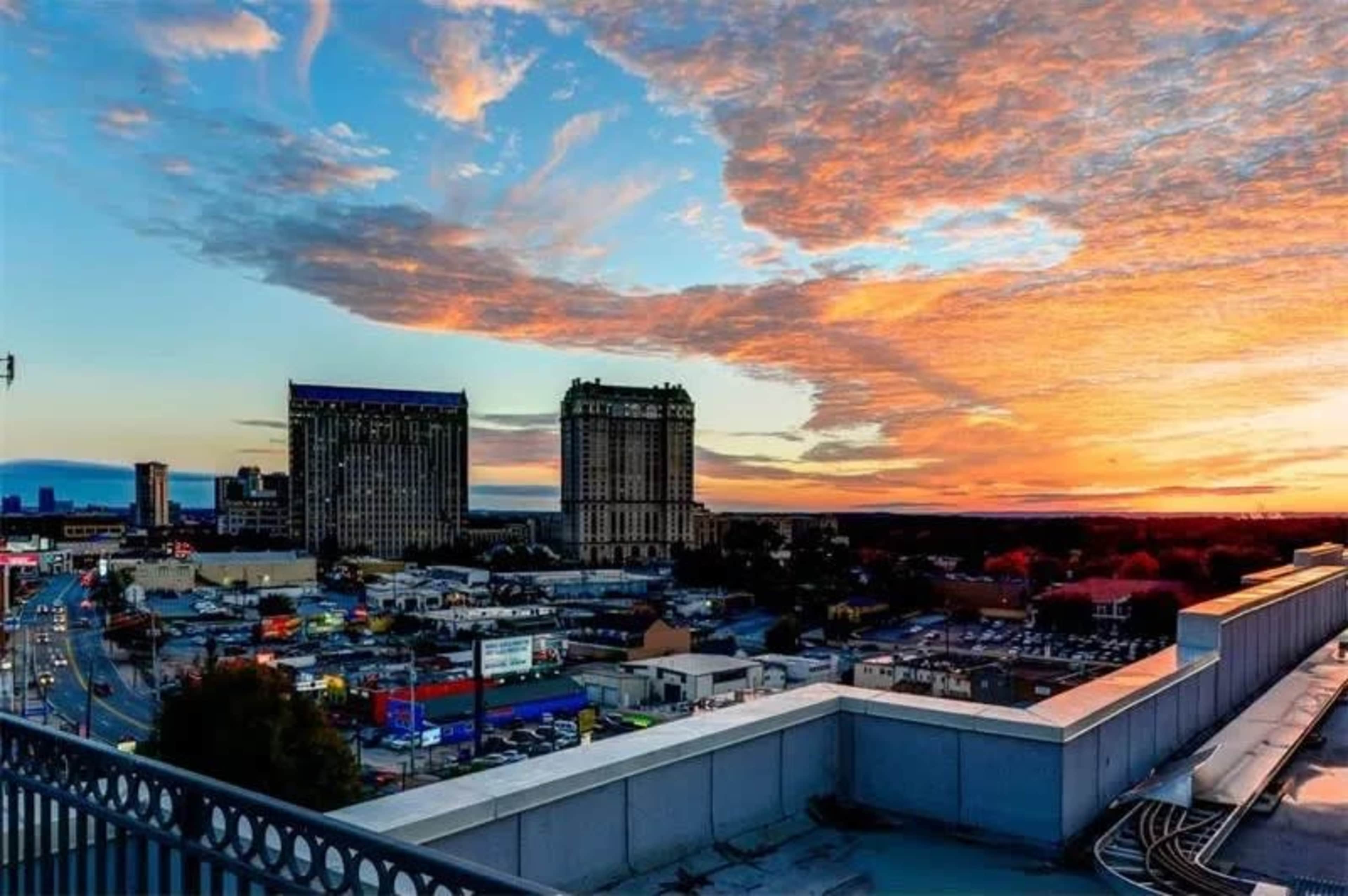 A vibrant sunset over a city skyline, with tall buildings and a mix of urban structures below.