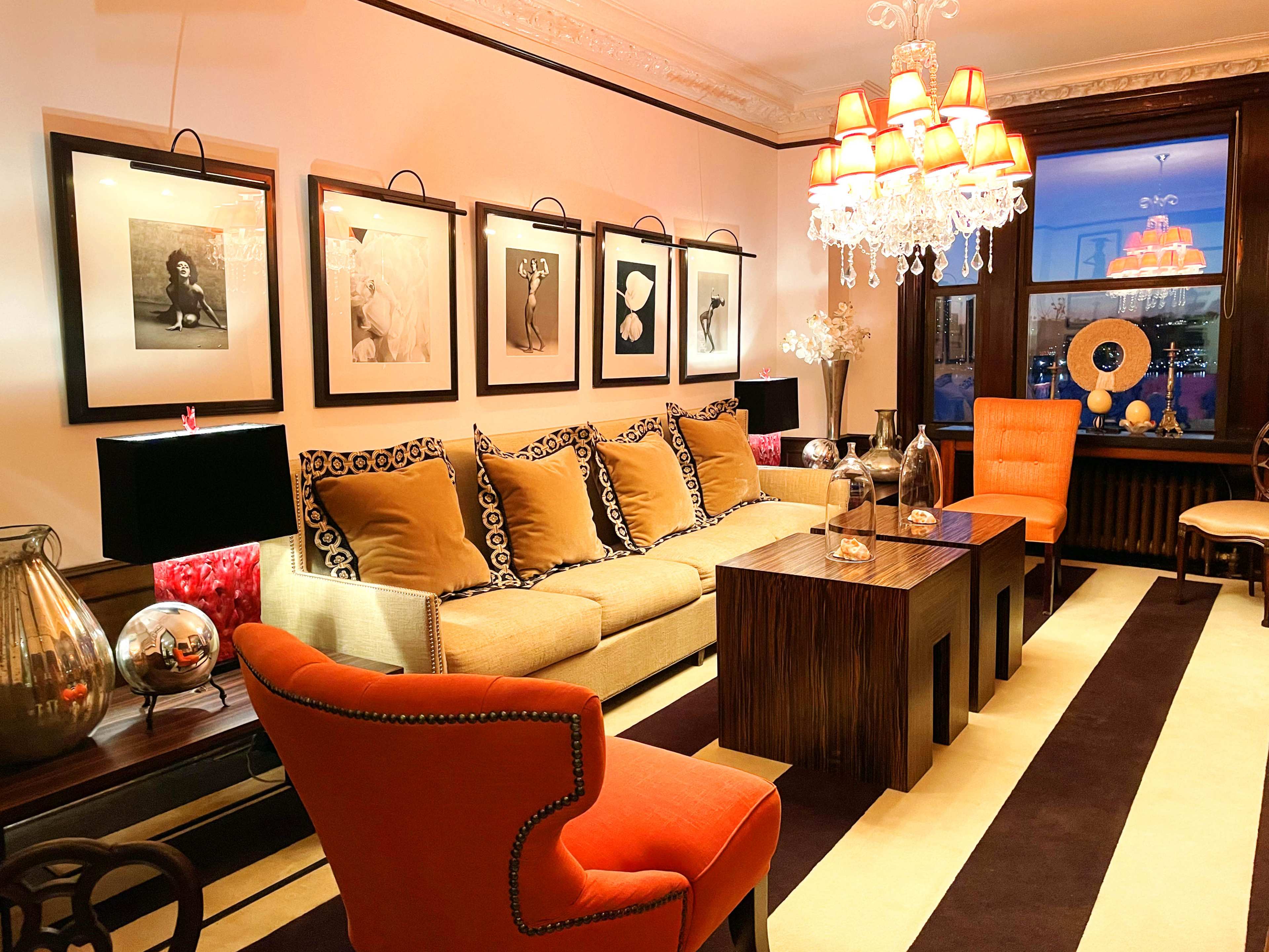 The scene features a stylish living room with a sofa adorned with decorative pillows, a wooden coffee table, and framed photographs on the wall, illuminated by a chandelier.