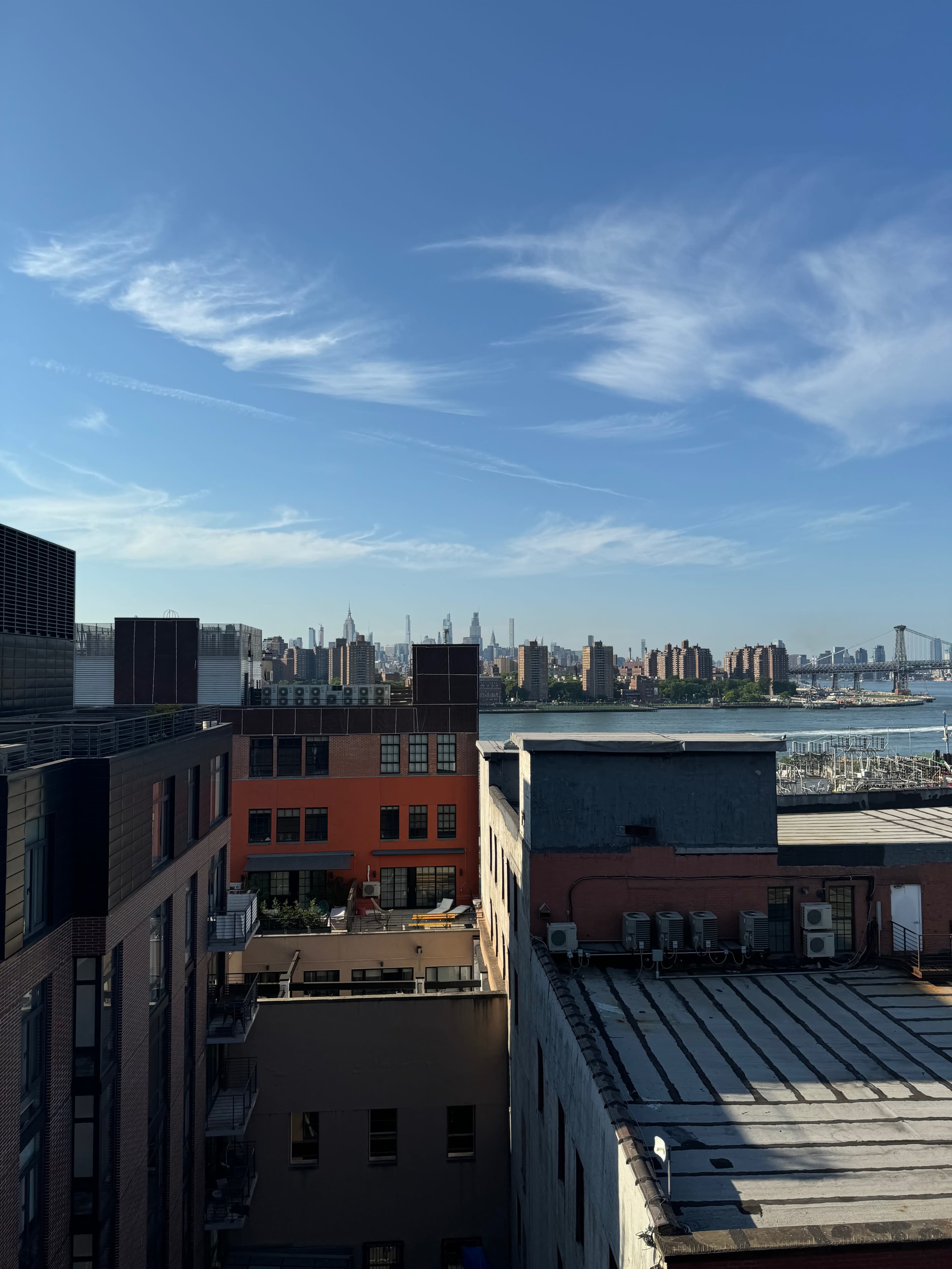 A view of a city skyline with buildings in the foreground and a clear blue sky above.