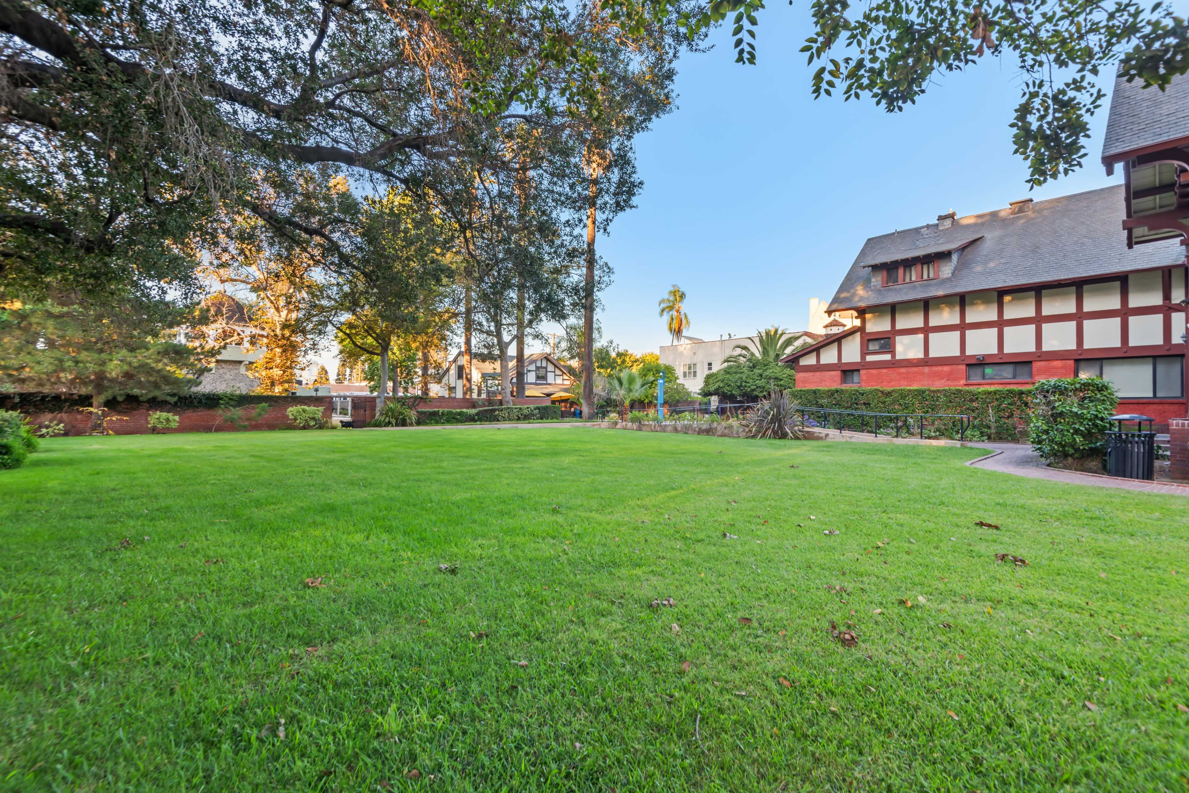The image shows a green lawn surrounded by trees and buildings in a residential area.