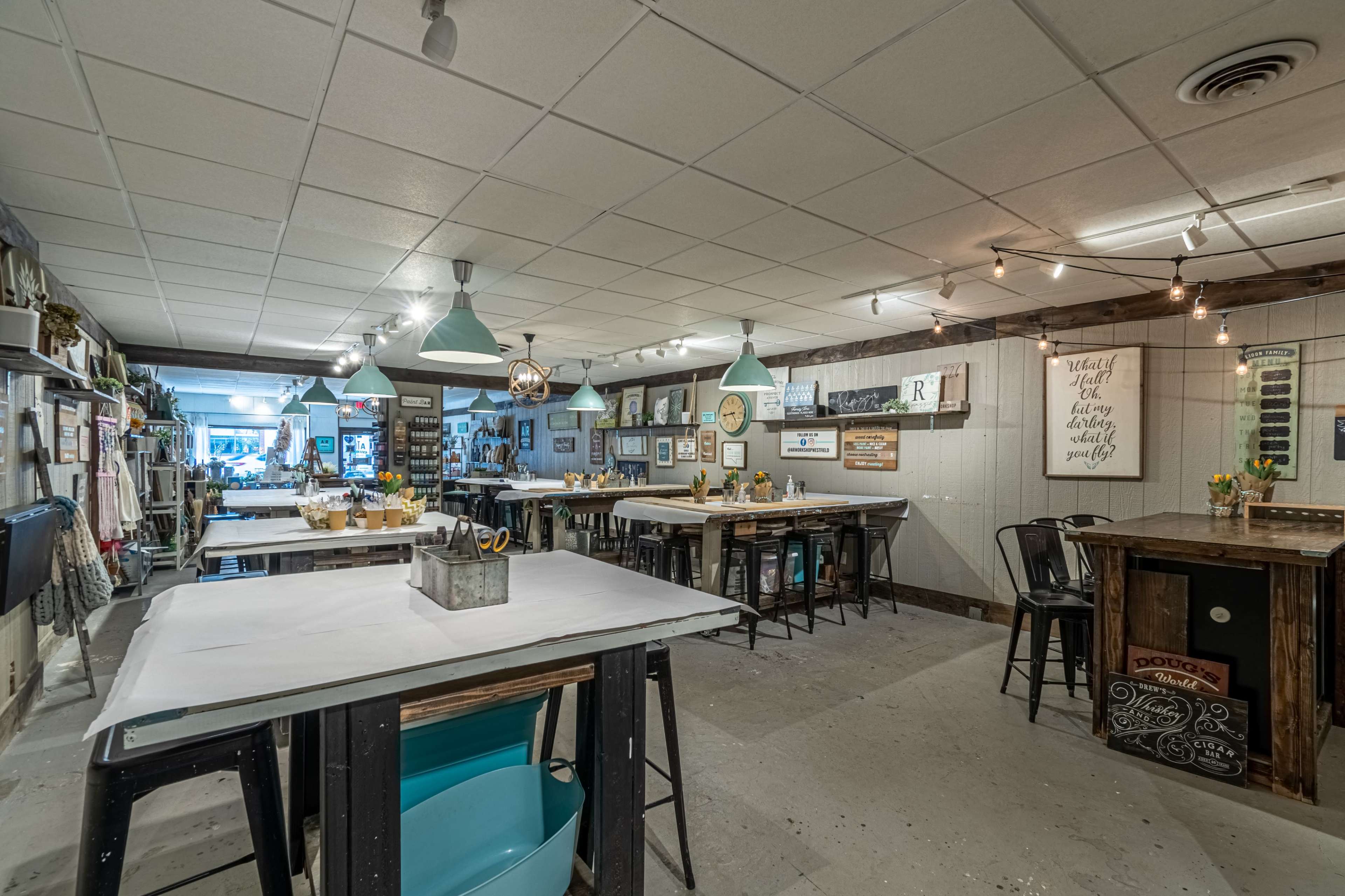 A spacious workshop or craft studio with tables for crafting, decorated walls, and various art supplies arranged around the room.