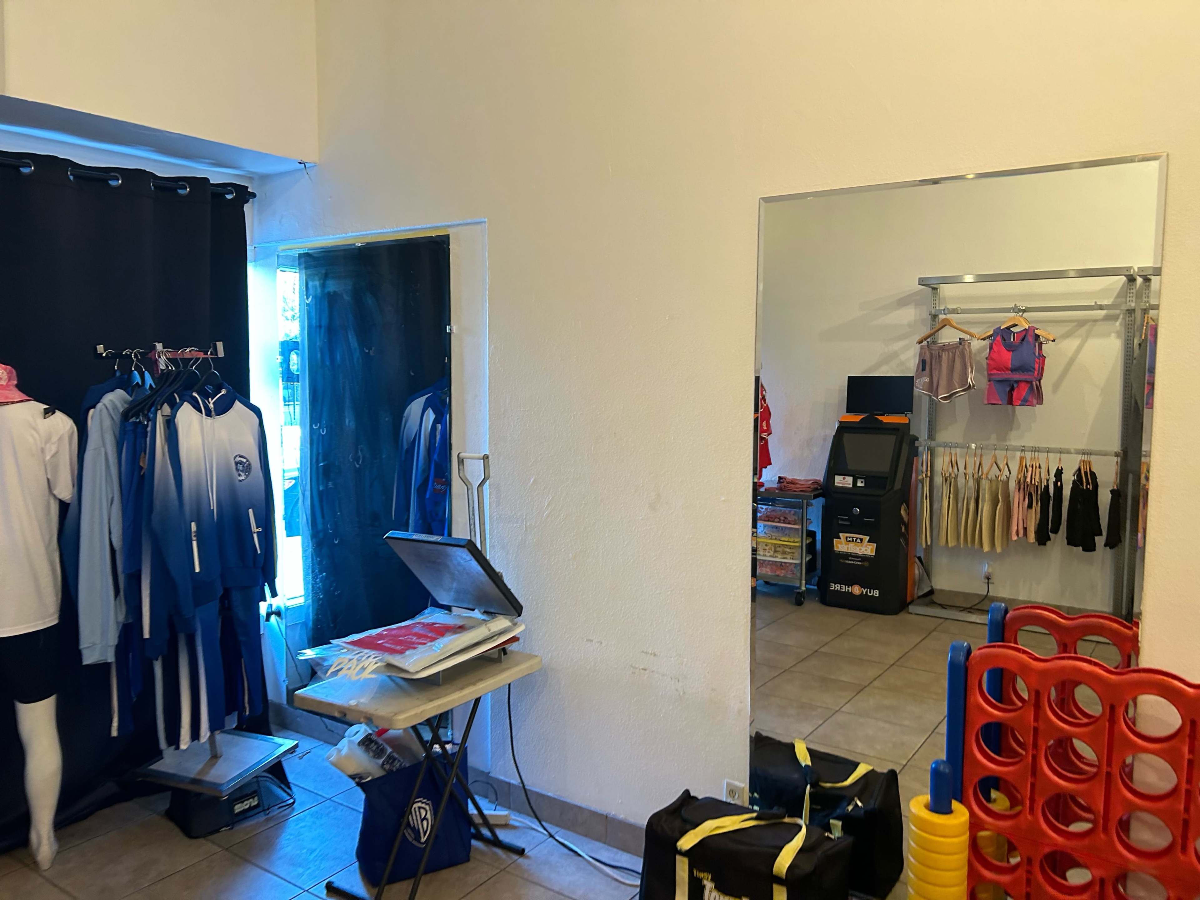 The image shows a clothing store interior with mirrors, displaying various garments on hangers and a stacking toy in the foreground.