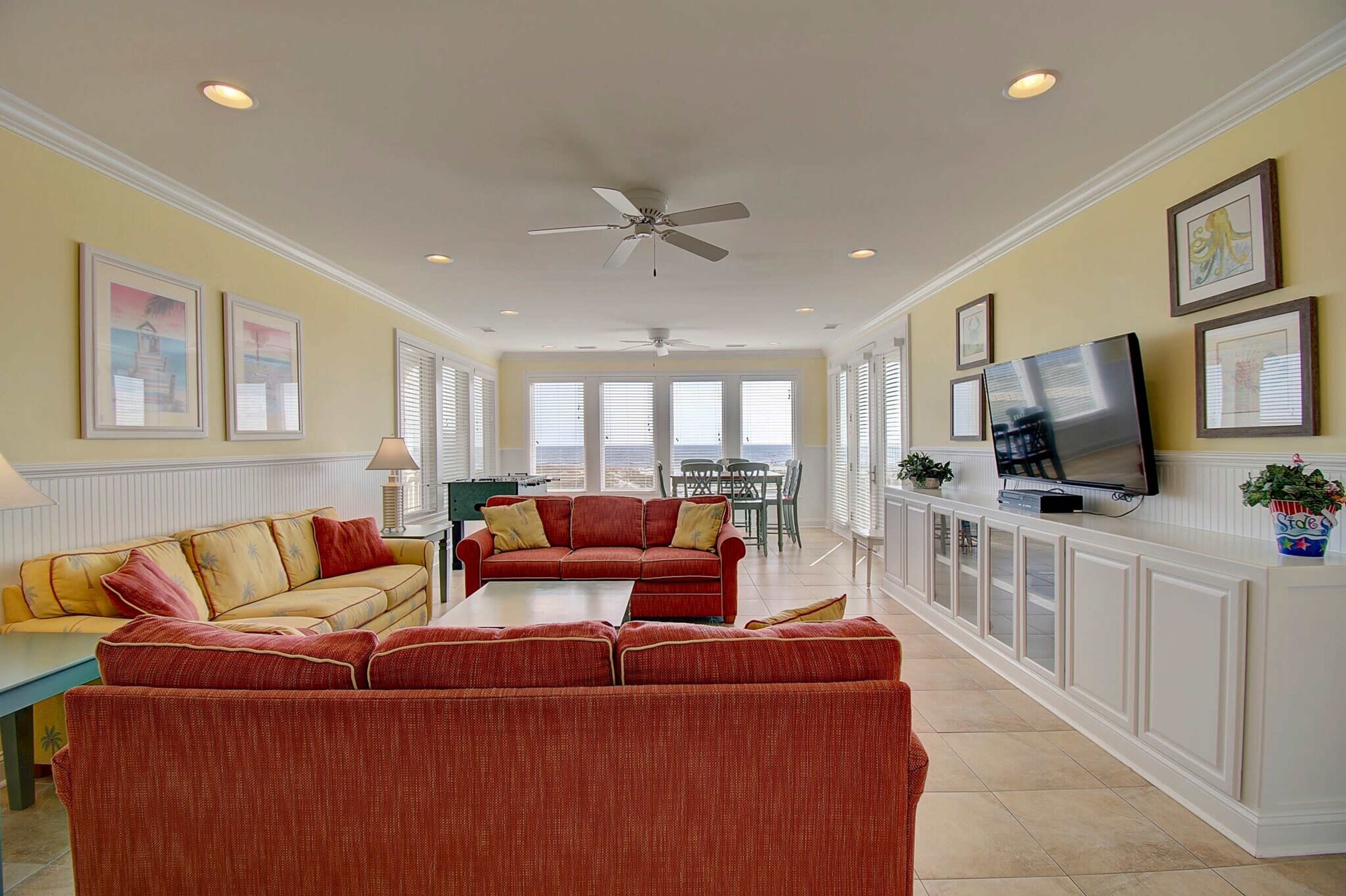 A bright and airy living room with two sofas, a coffee table, and large windows offering a view of the outside.