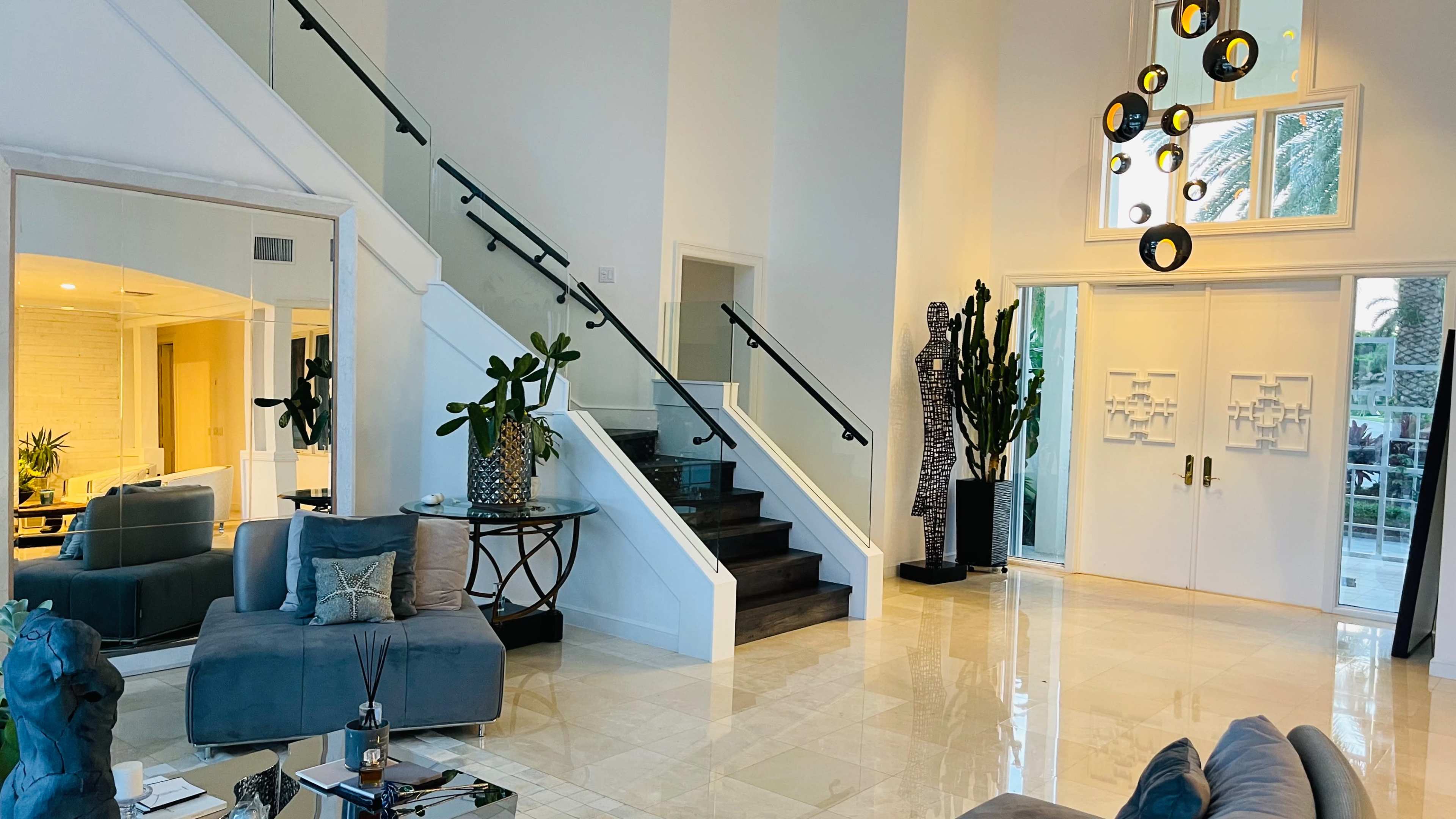 A spacious and well-lit foyer with a staircase, modern decor, and large windows.