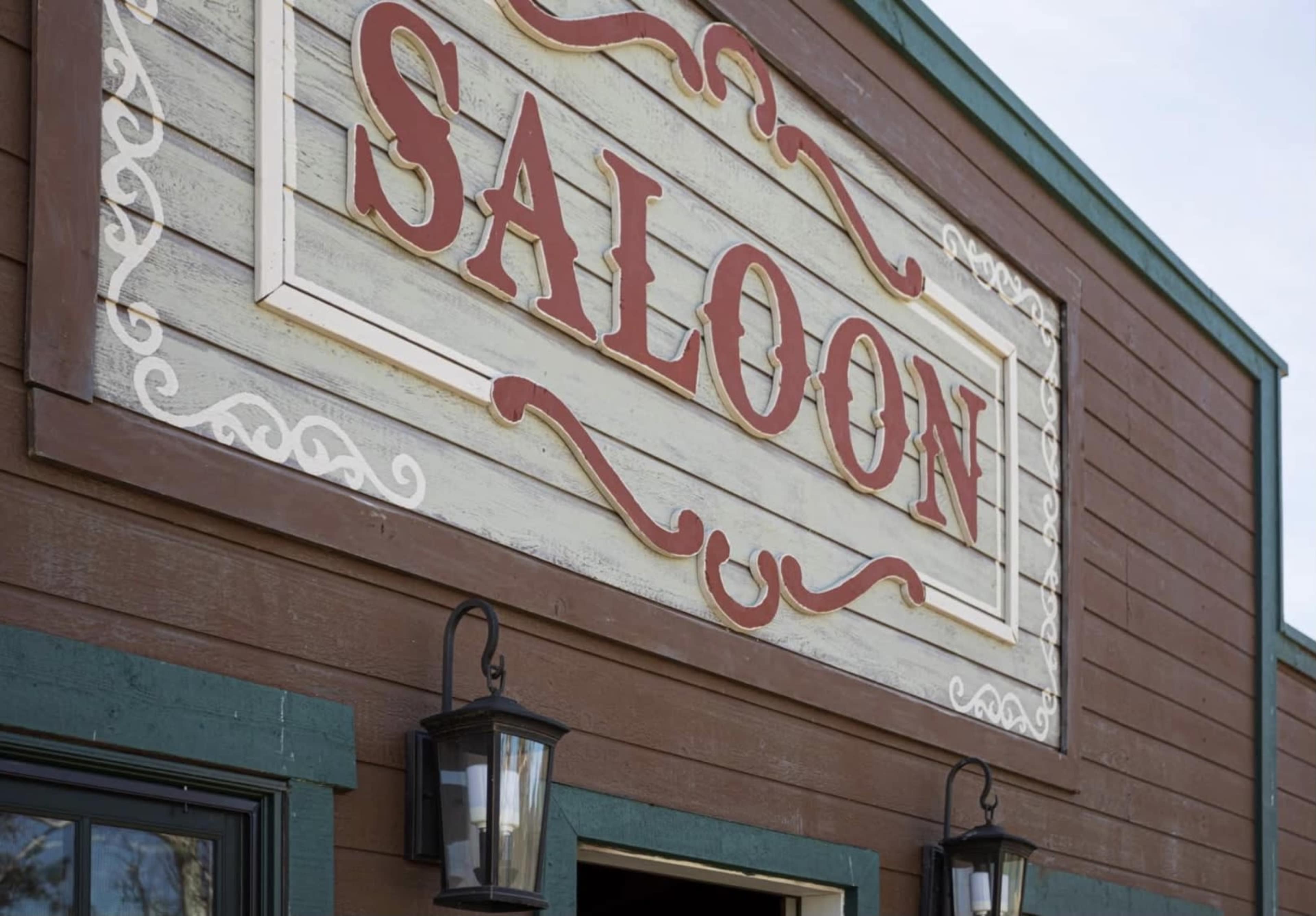 A close-up of a wooden building with a prominent sign that reads "SALOON."