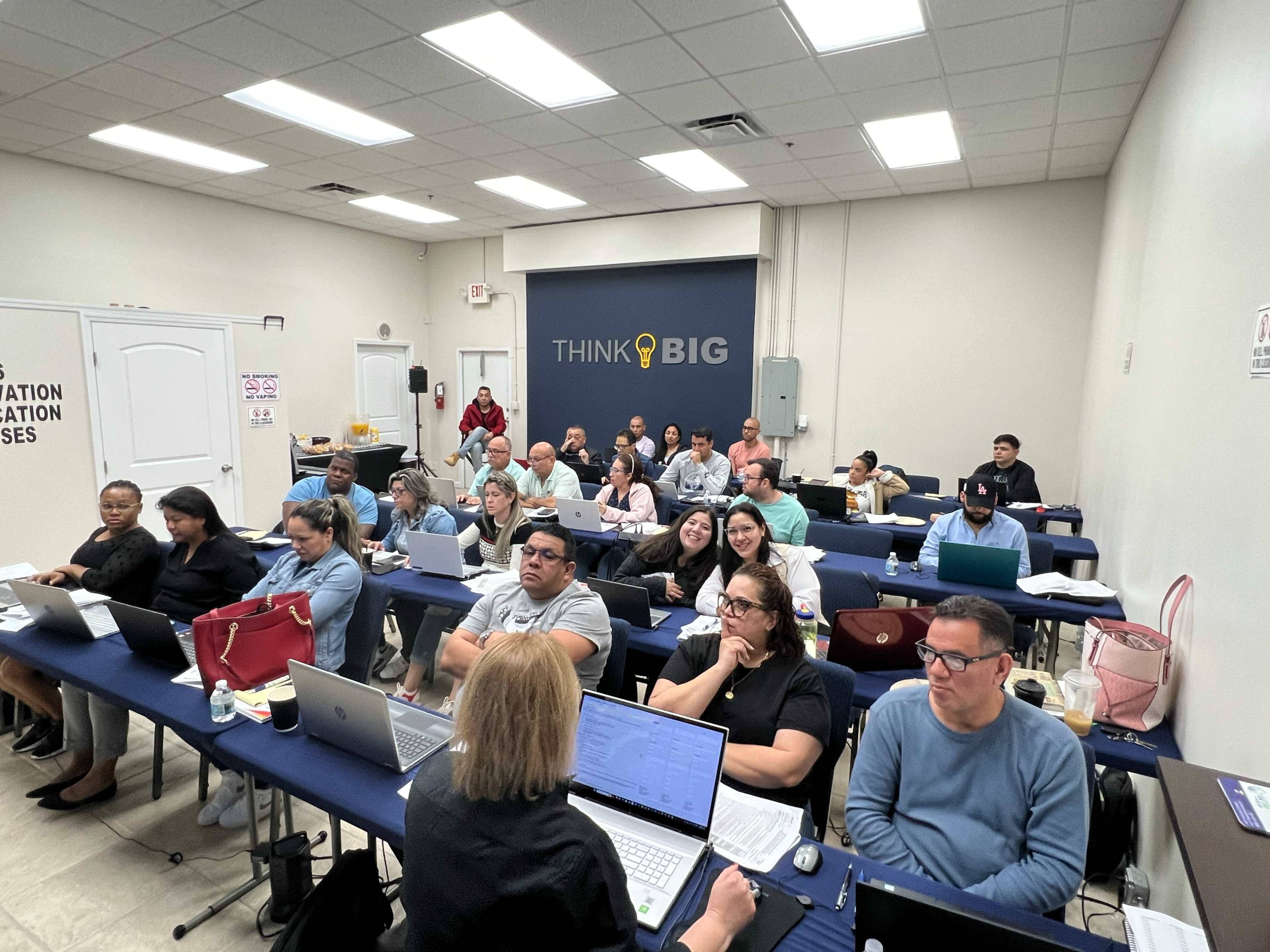 A classroom filled with students seated at desks, engaged in a lesson while using laptops.