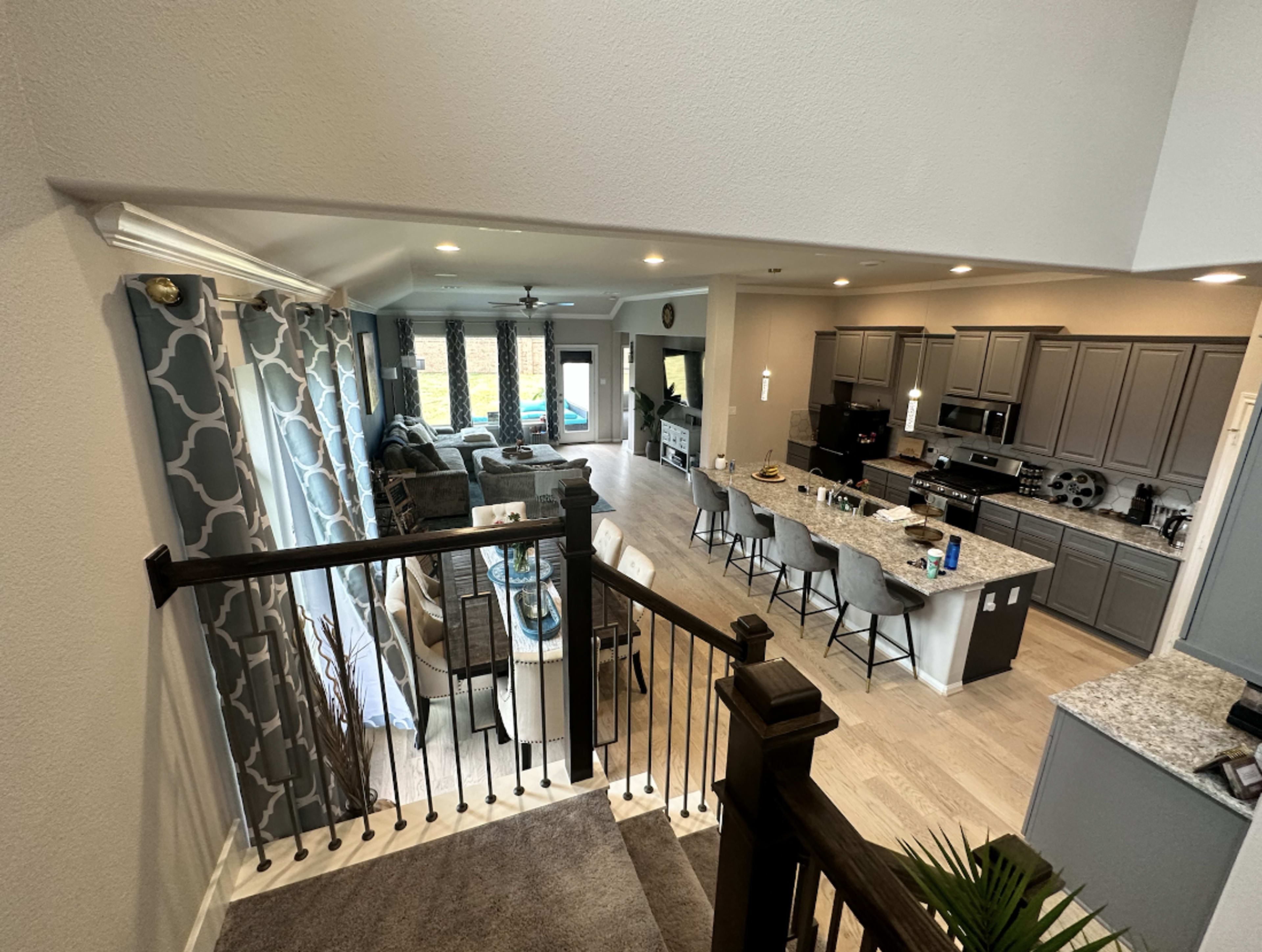 A modern open-concept living space with a kitchen island, dining area, and a living room featuring large windows.