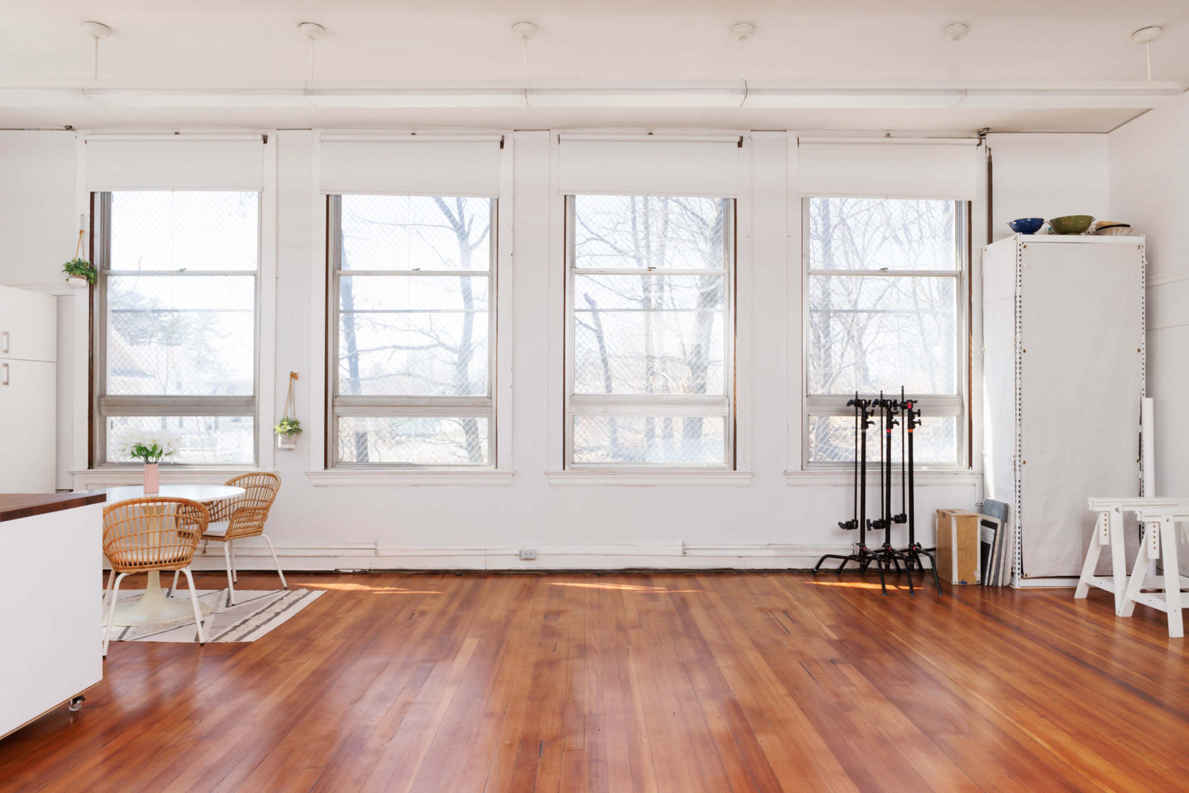 A bright room with large windows and wooden flooring features a dining area with two chairs and a table.