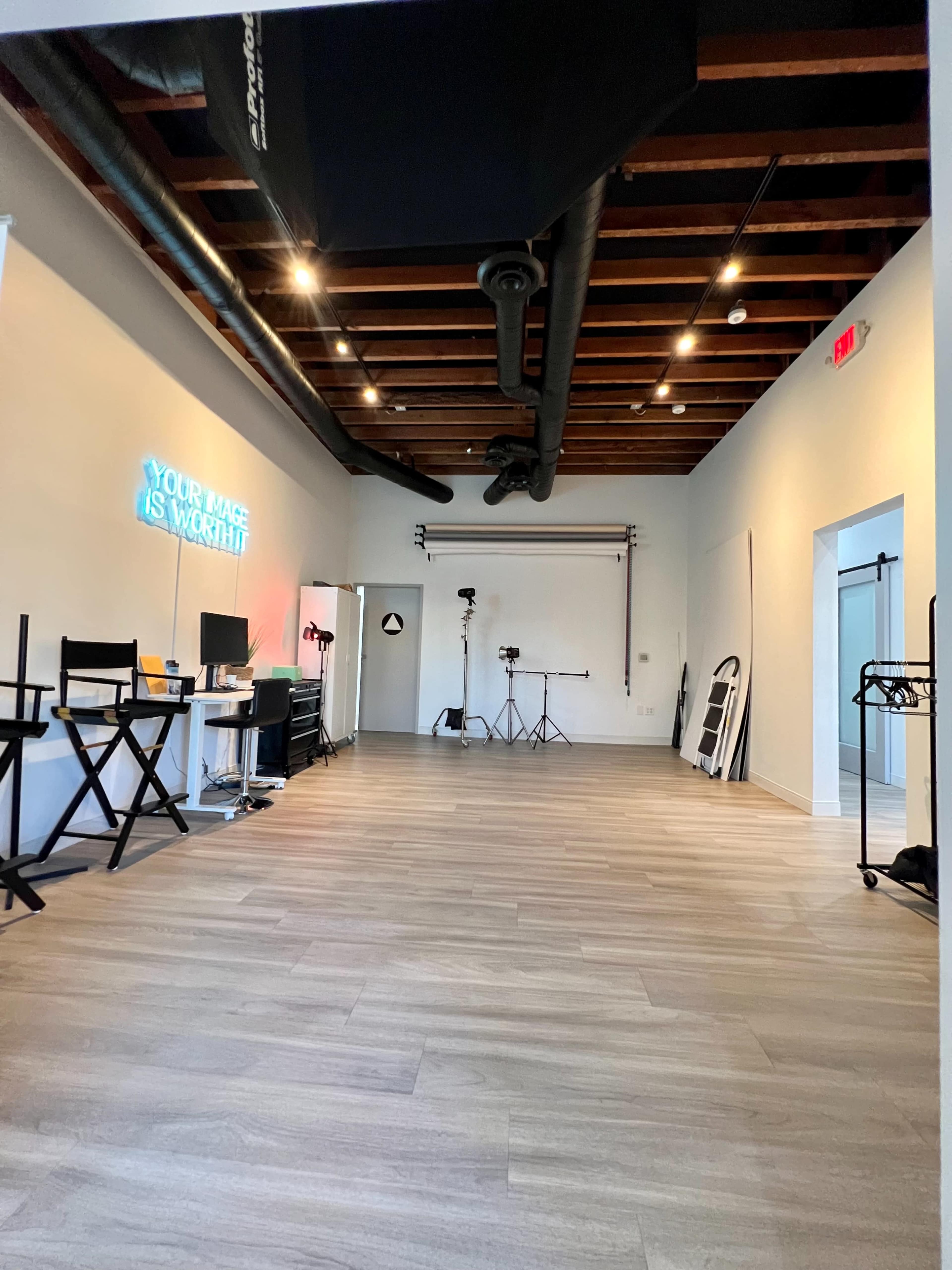 A spacious studio with wooden beams and a variety of equipment set up for photography.