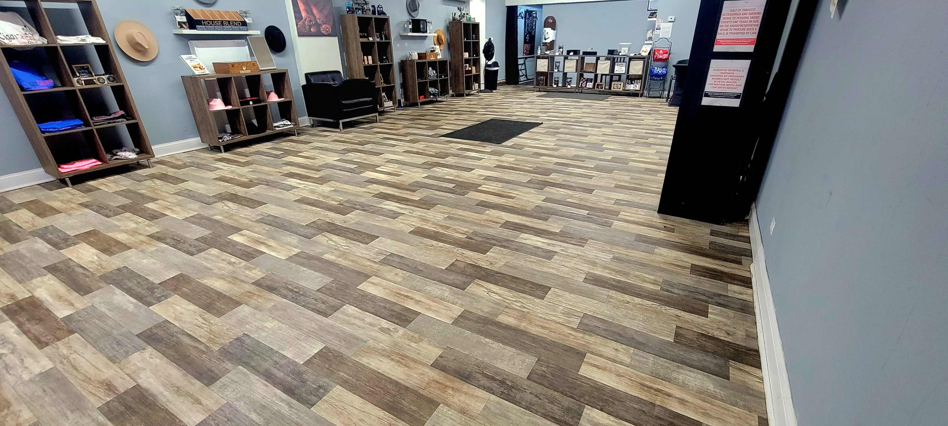 The image shows a retail space with wooden-style flooring, displaying shelves of merchandise on the sides and an empty central area.