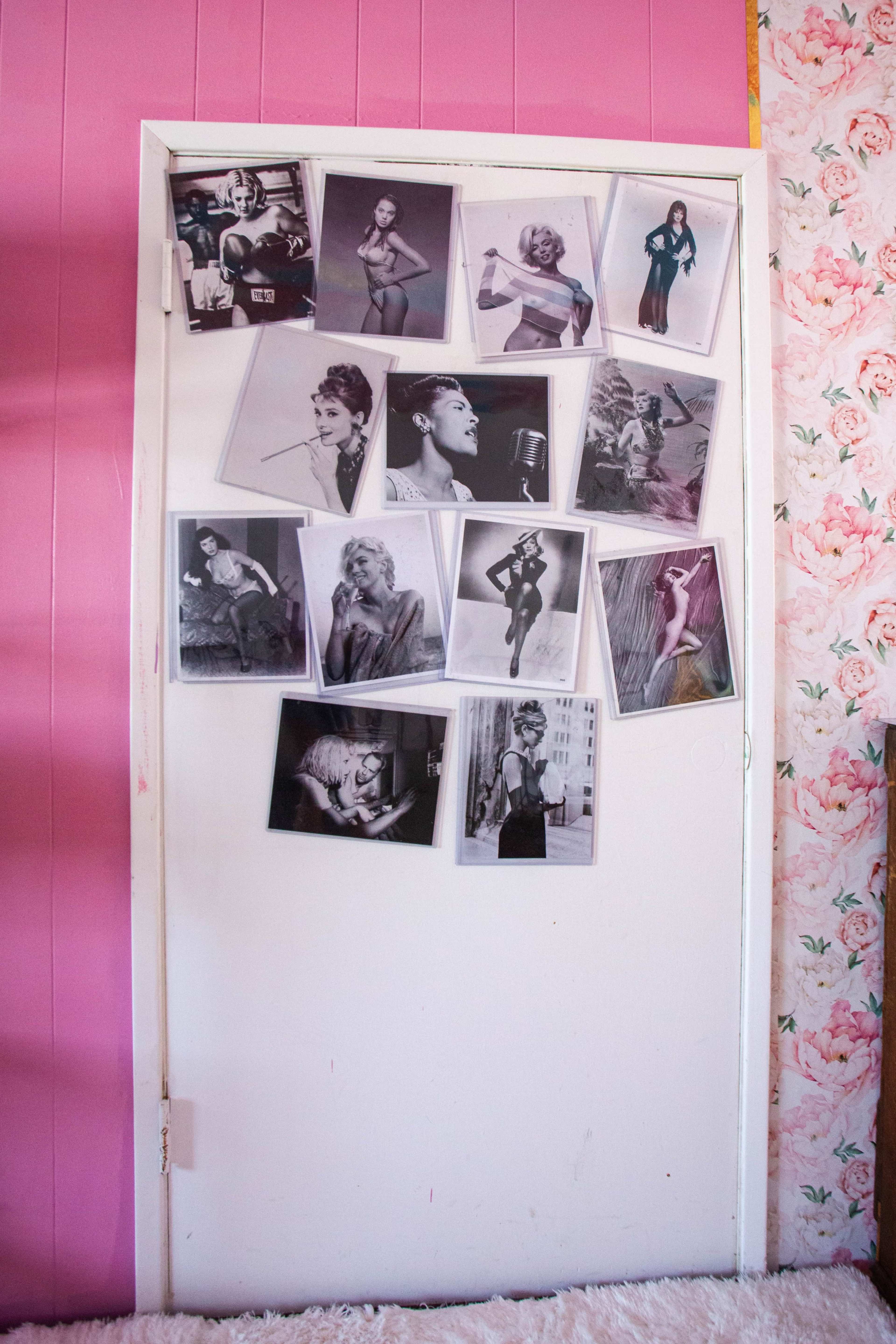 A white door is adorned with various black-and-white photographs of models and celebrities against a pink wall.