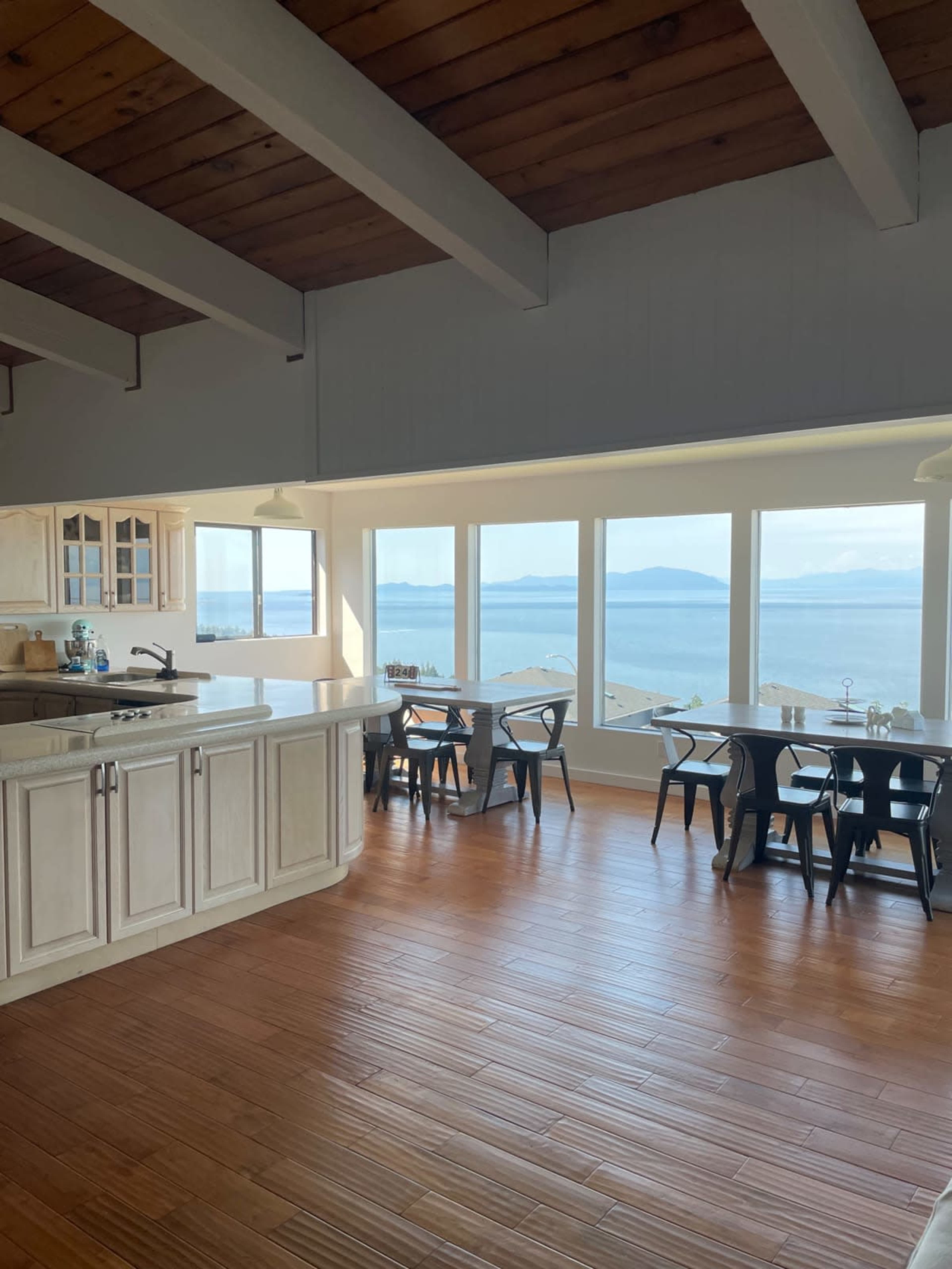 A spacious kitchen and dining area with large windows offering a view of the ocean and distant islands.